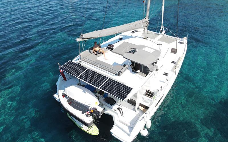 2022 Fountaine Pajot Elba 45 catamaran with solar panels, anchored in clear blue water.