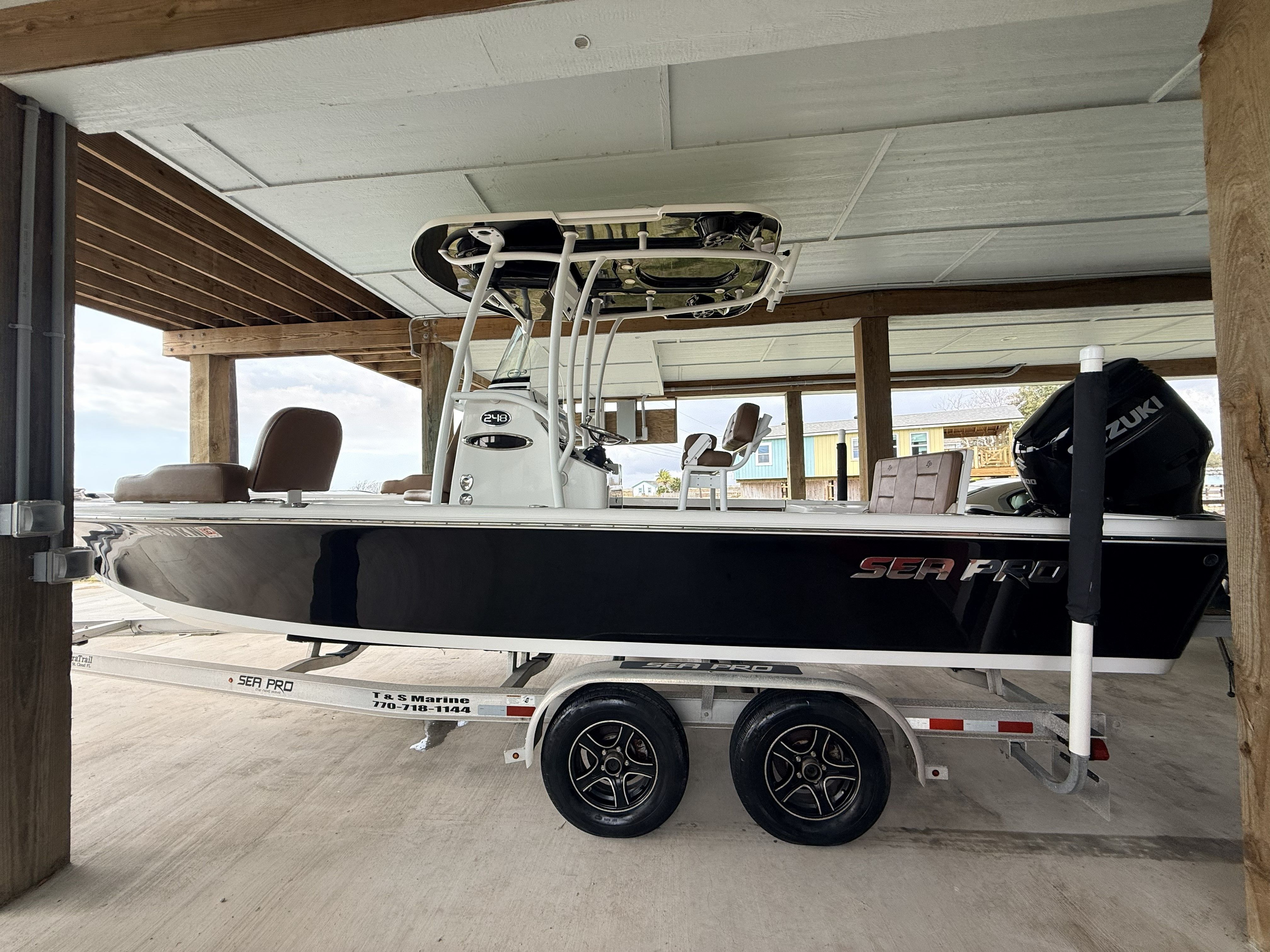 A black Sea Pro 248 Bay boat is on a trailer in a covered area.