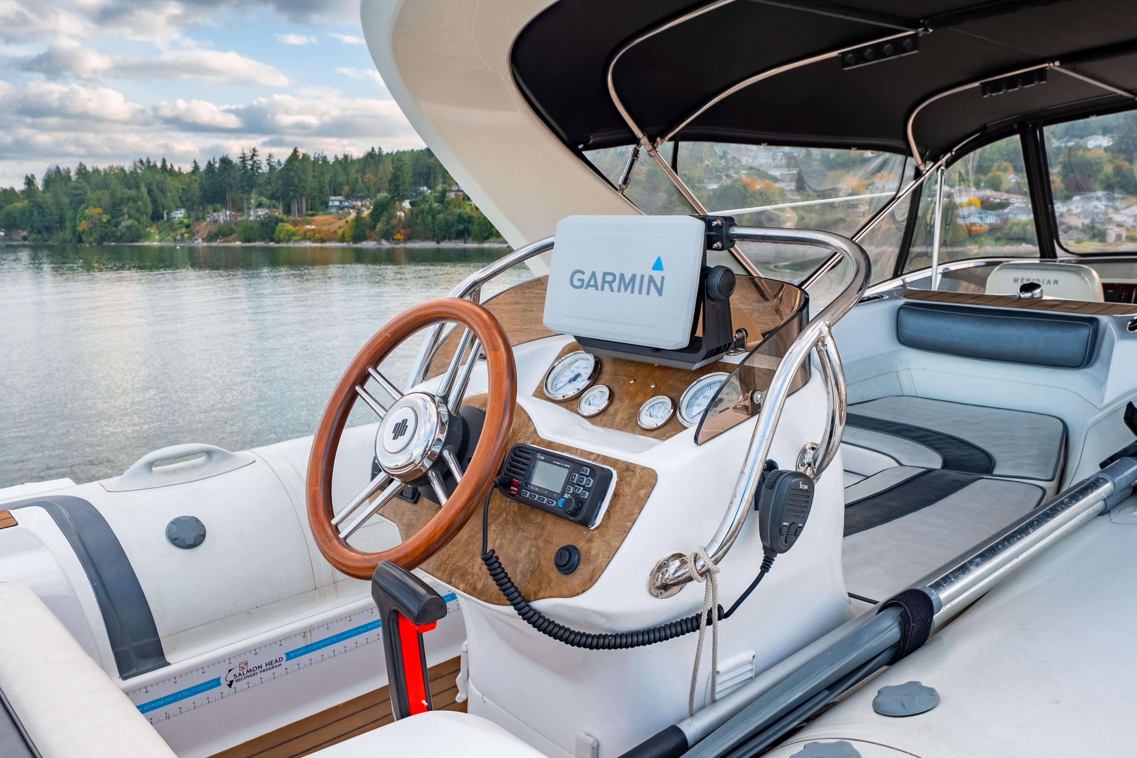 2007 Meridian 580 Pilothouse yacht helm with Garmin navigation, on a serene lake backdrop.