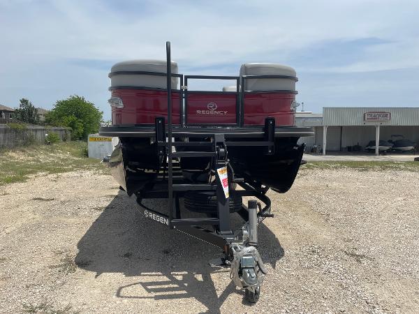 2023 Regency 250 DL3 pontoon boat on a trailer, parked outdoors.