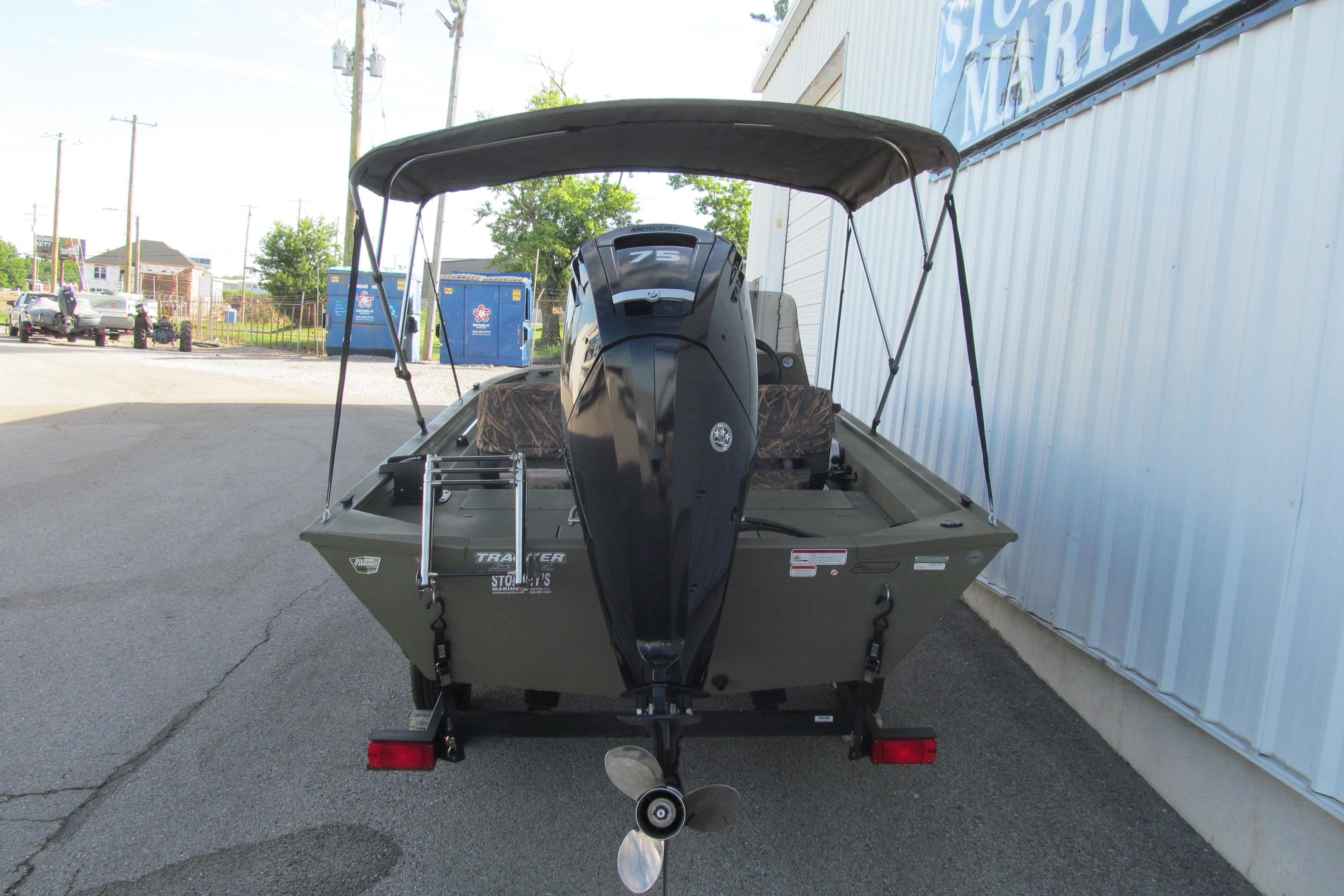 2018 Tracker Grizzly 1754 SC boat with outboard motor and canopy, parked outdoors.
