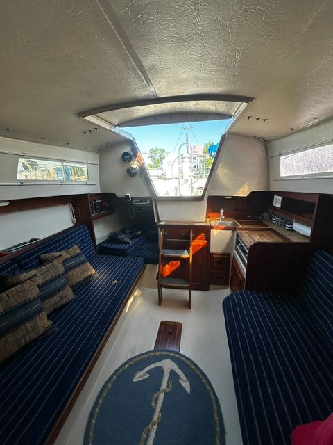 Interior of a 1985 Catalina 27 with blue seating and wooden furnishings.