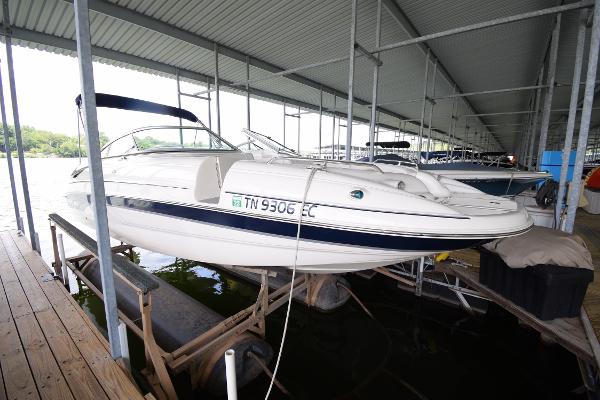 A white boat on a lift in a covered dock.