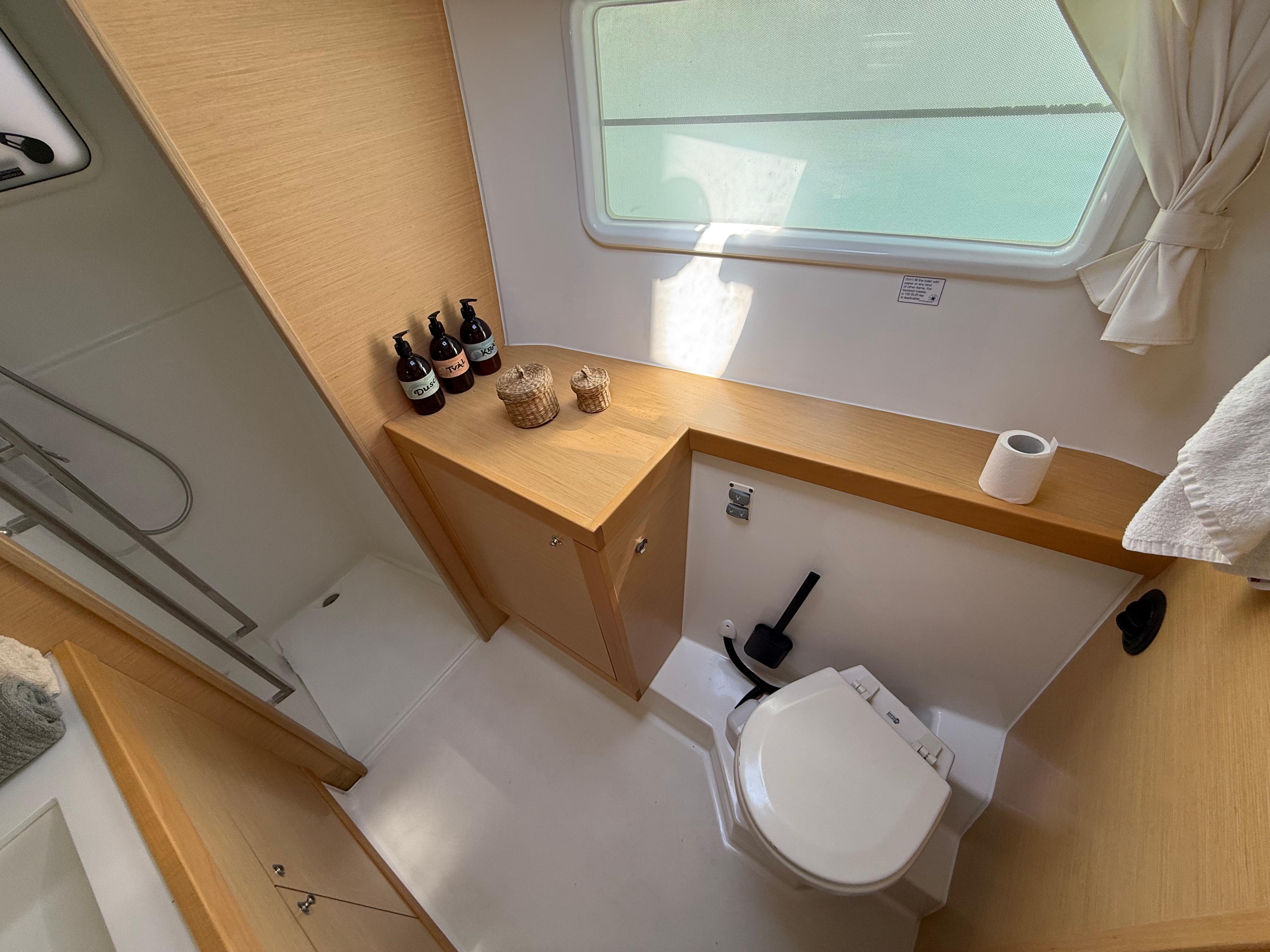 Modern bathroom interior of 2017 Lagoon 400 S2 yacht, featuring wooden accents and natural light.