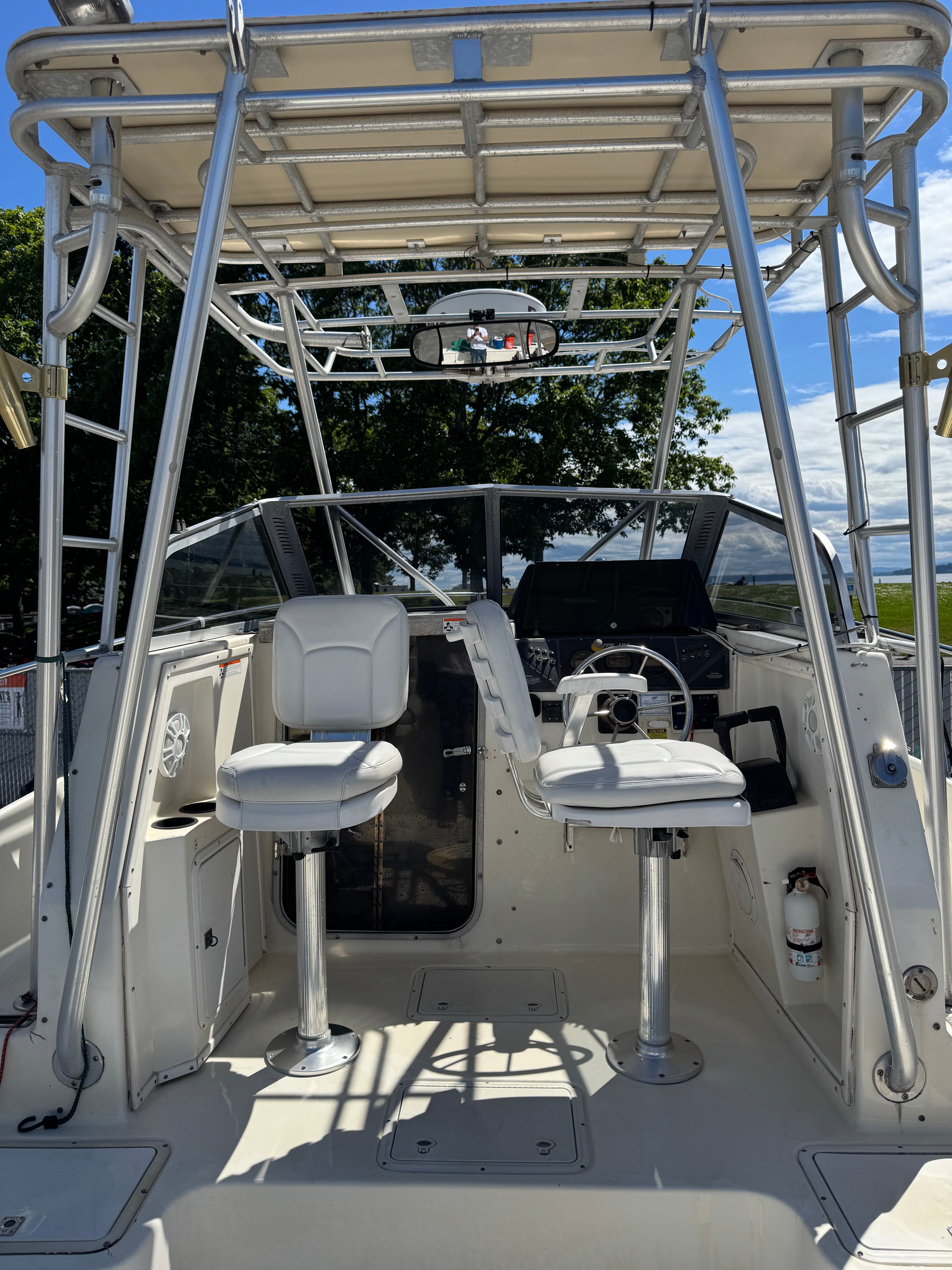The boat features two white seats and a steering wheel under a canopy.