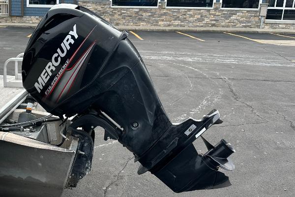 A Mercury outboard motor is attached to a boat parked in a lot.
