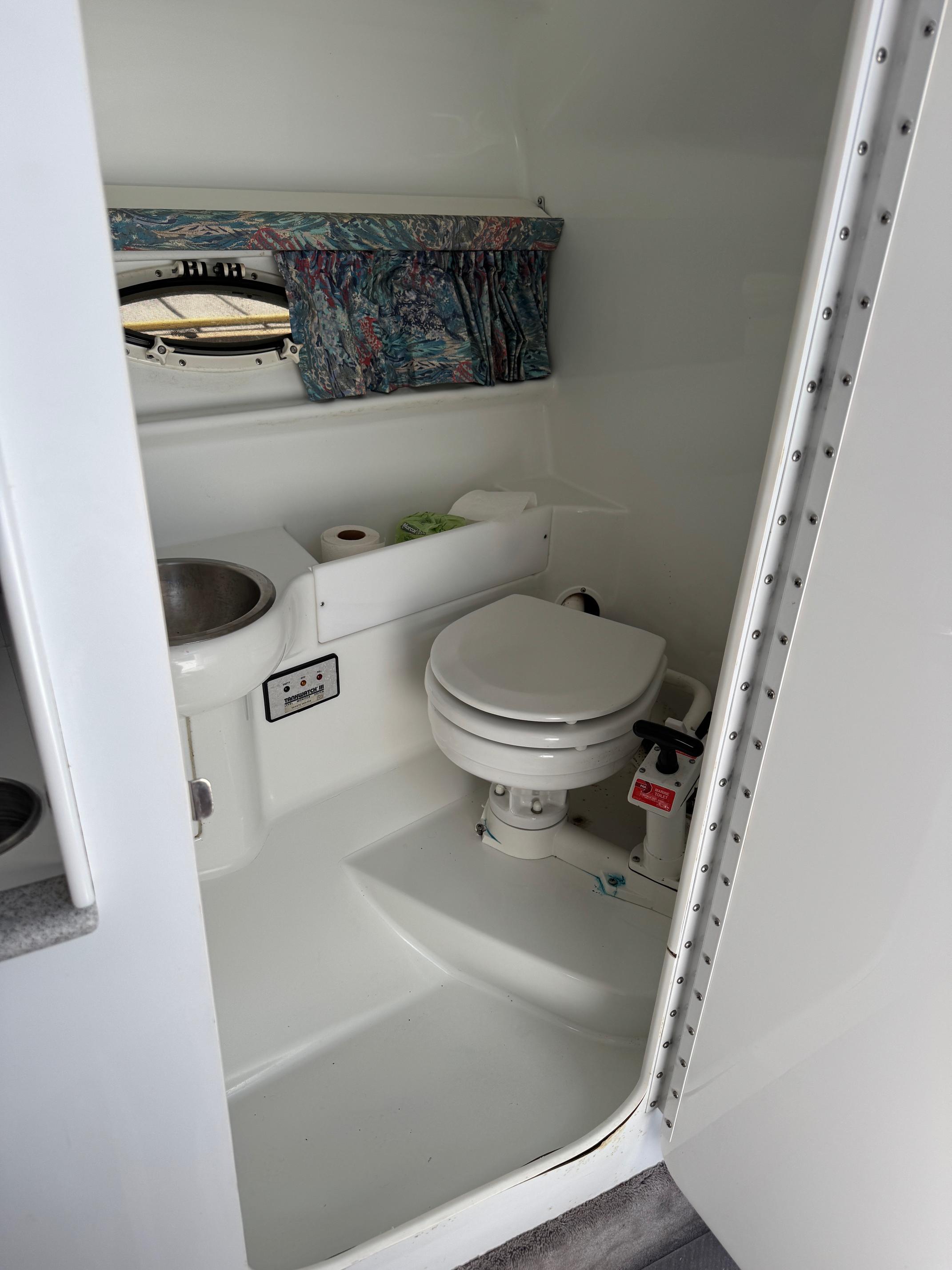 Compact bathroom in a 1996 Formula 280 SS boat, featuring a toilet and sink.
