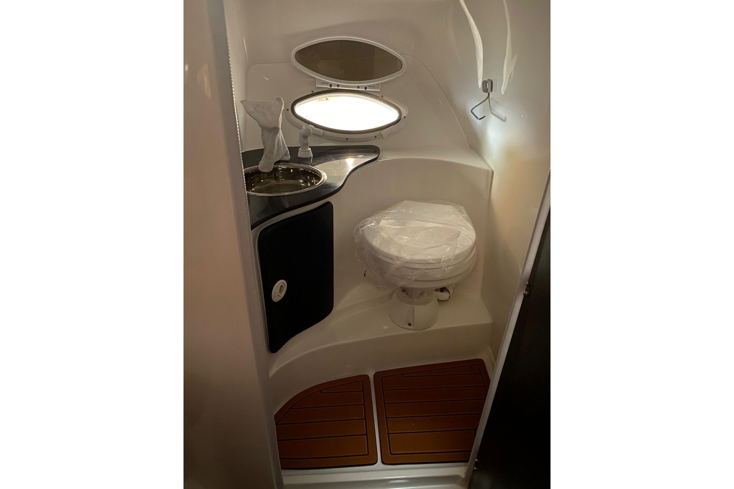 Compact bathroom in a 2026 Hanover 305 model, featuring a toilet and sink.