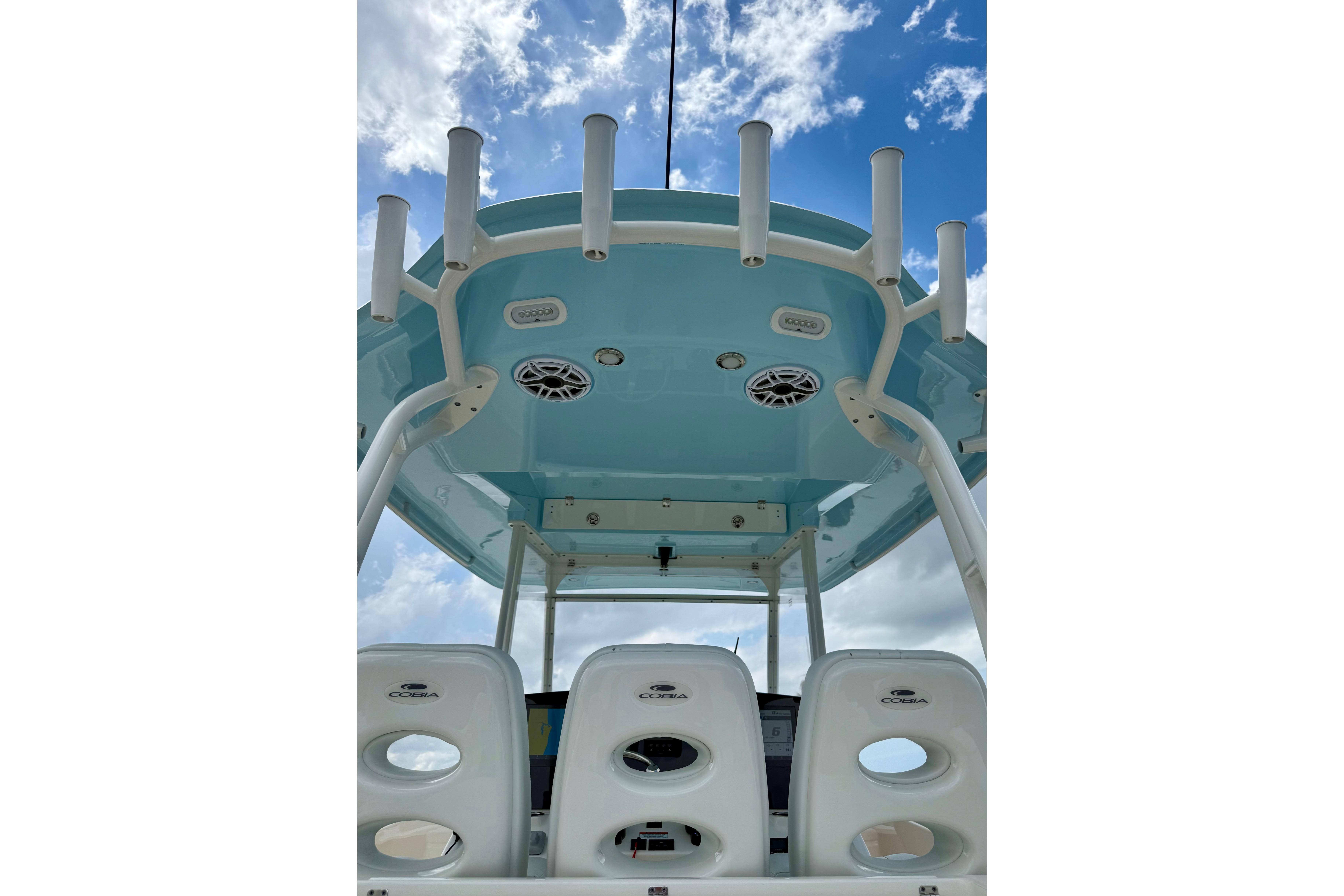 2023 Cobia 350 Center Console boat interior with rod holders and speakers under blue sky.