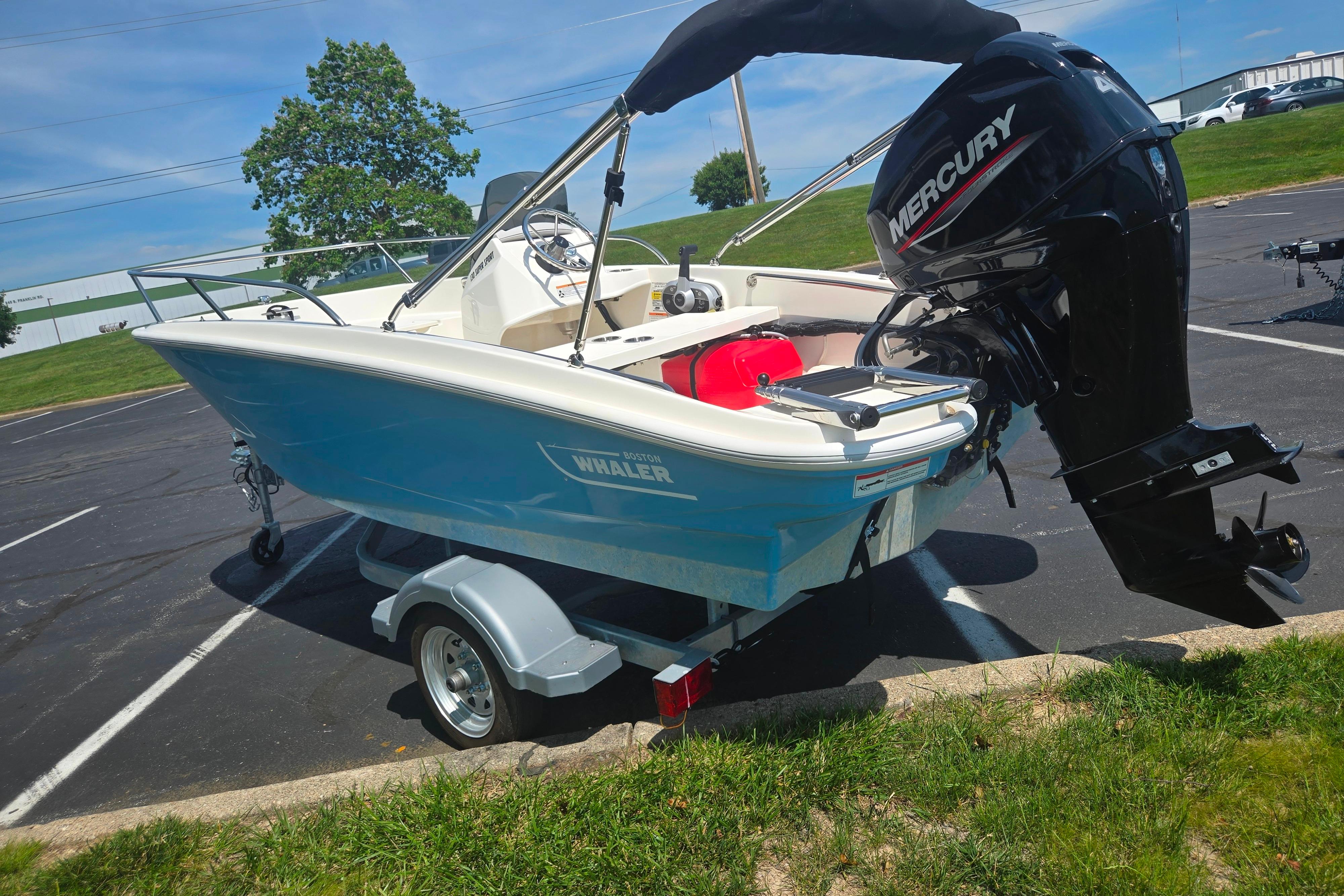 2025 Boston Whaler 130 Super Sport boat with Mercury engine on trailer in parking lot.