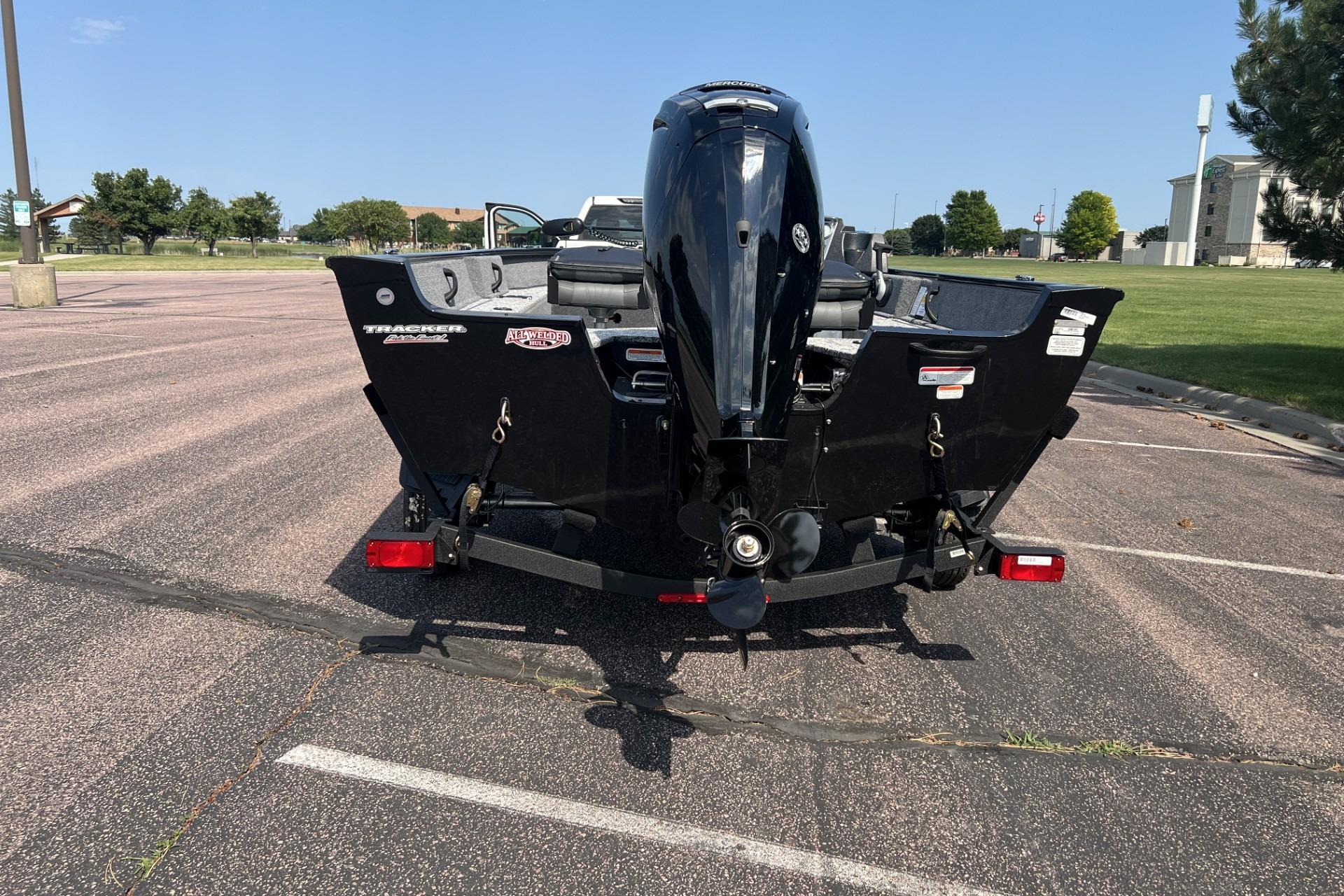2026 Tracker Pro Guide V-16 SC boat on trailer, rear view in parking lot.