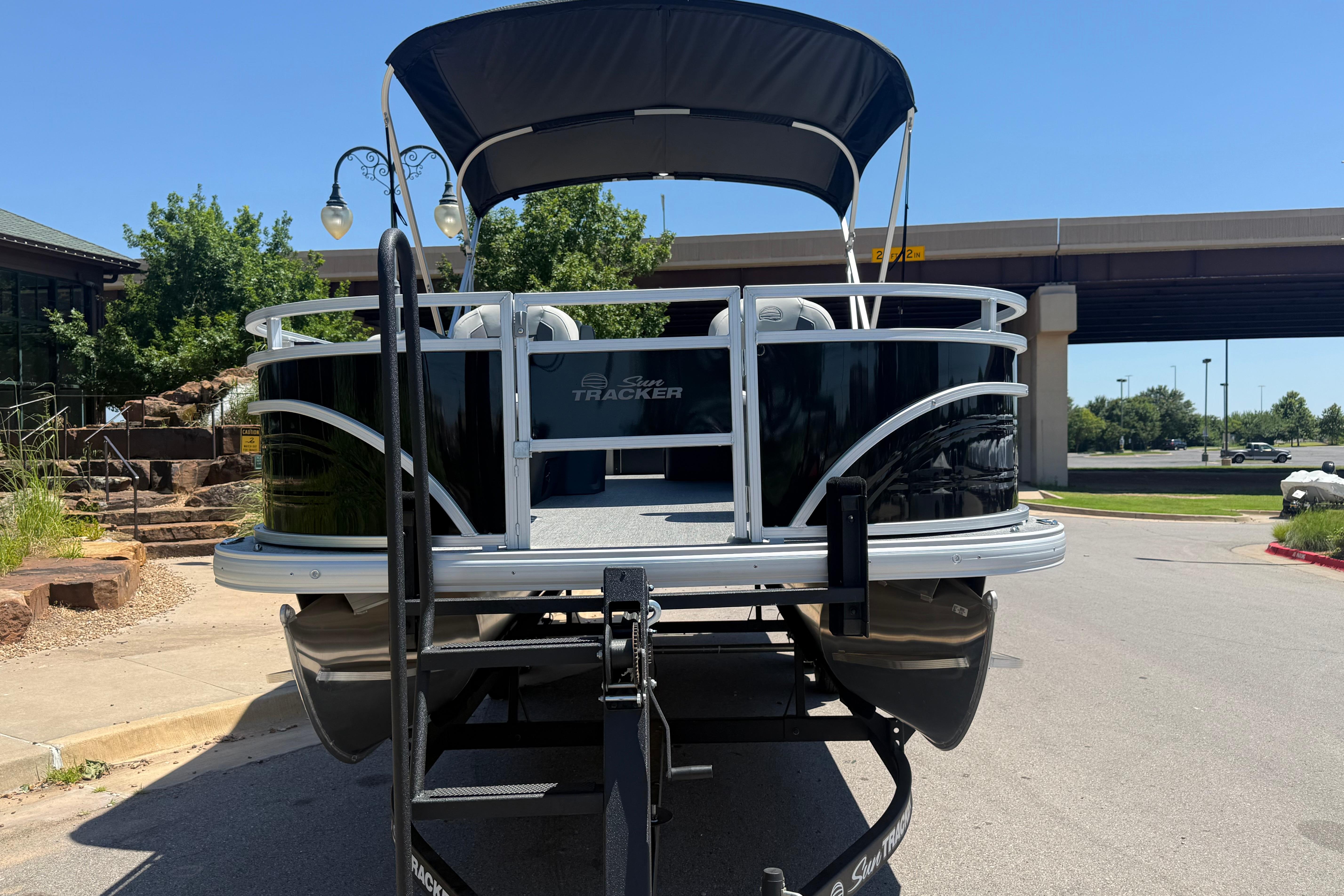 2026 Sun Tracker Fishin' Barge 22 DLX pontoon boat on trailer, parked outdoors.