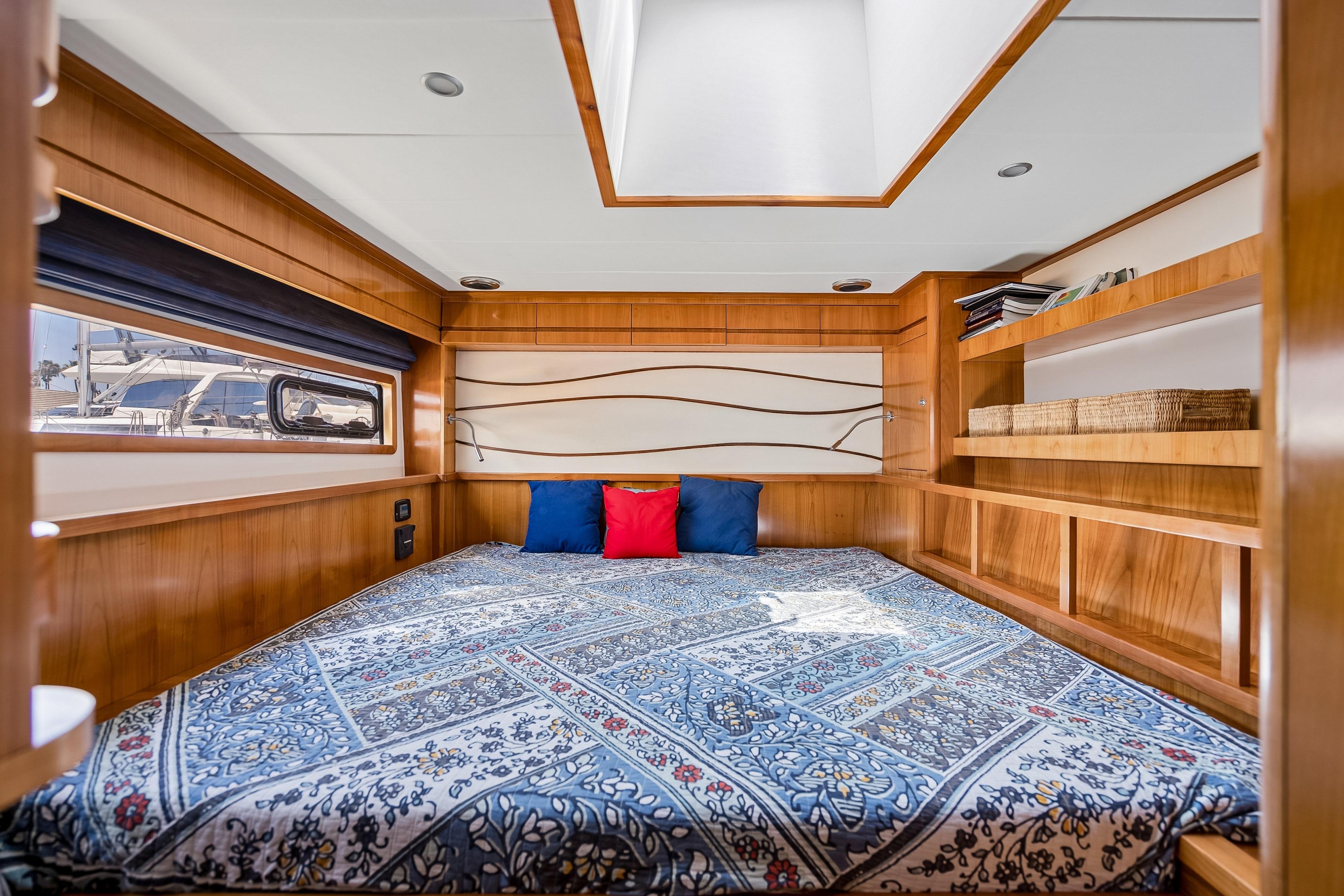Luxurious Catana 65 yacht bedroom with elegant wood finish and patterned bedding, 2009 model.