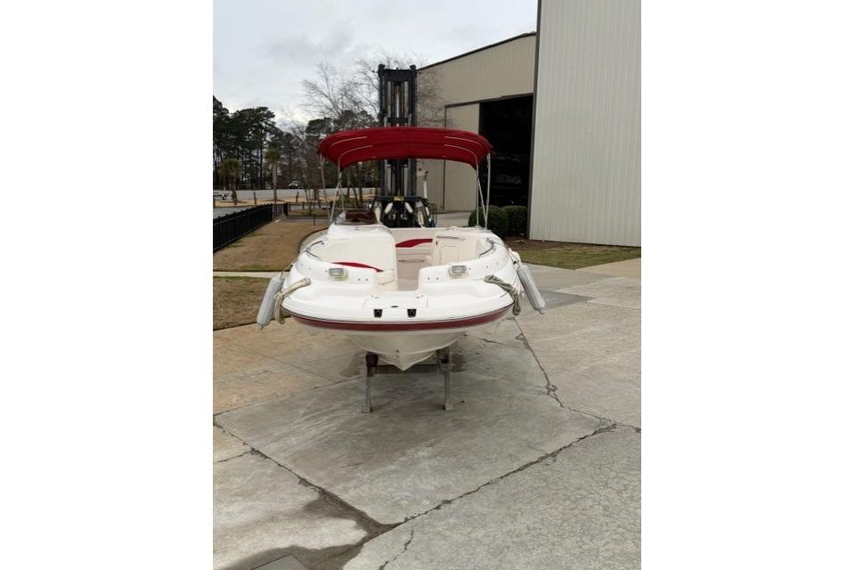 2000 Chaparral 232 Sunesta boat with red canopy, parked outside a building.