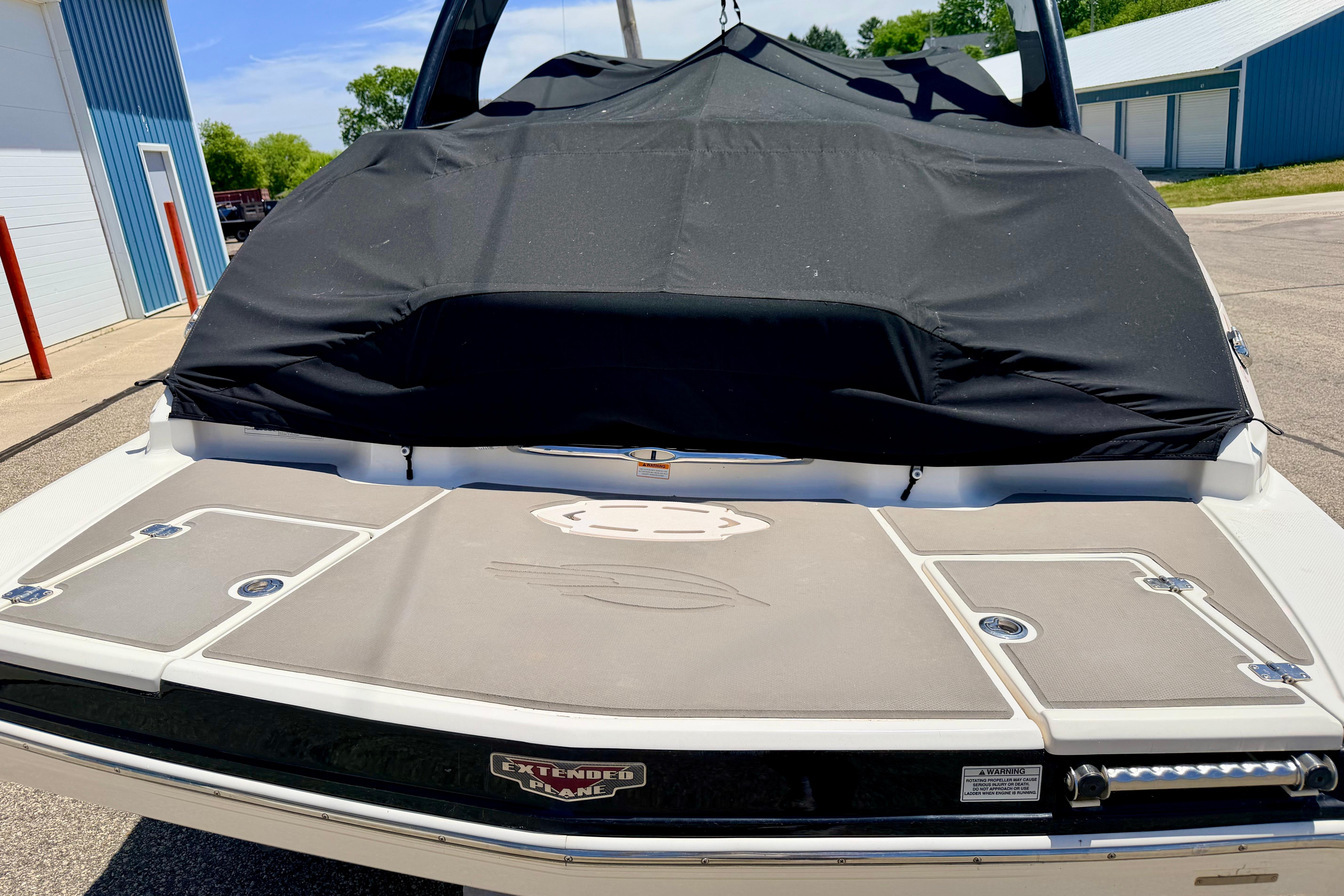 2015 Chaparral Sunesta 264 boat with black cover, docked outdoors.