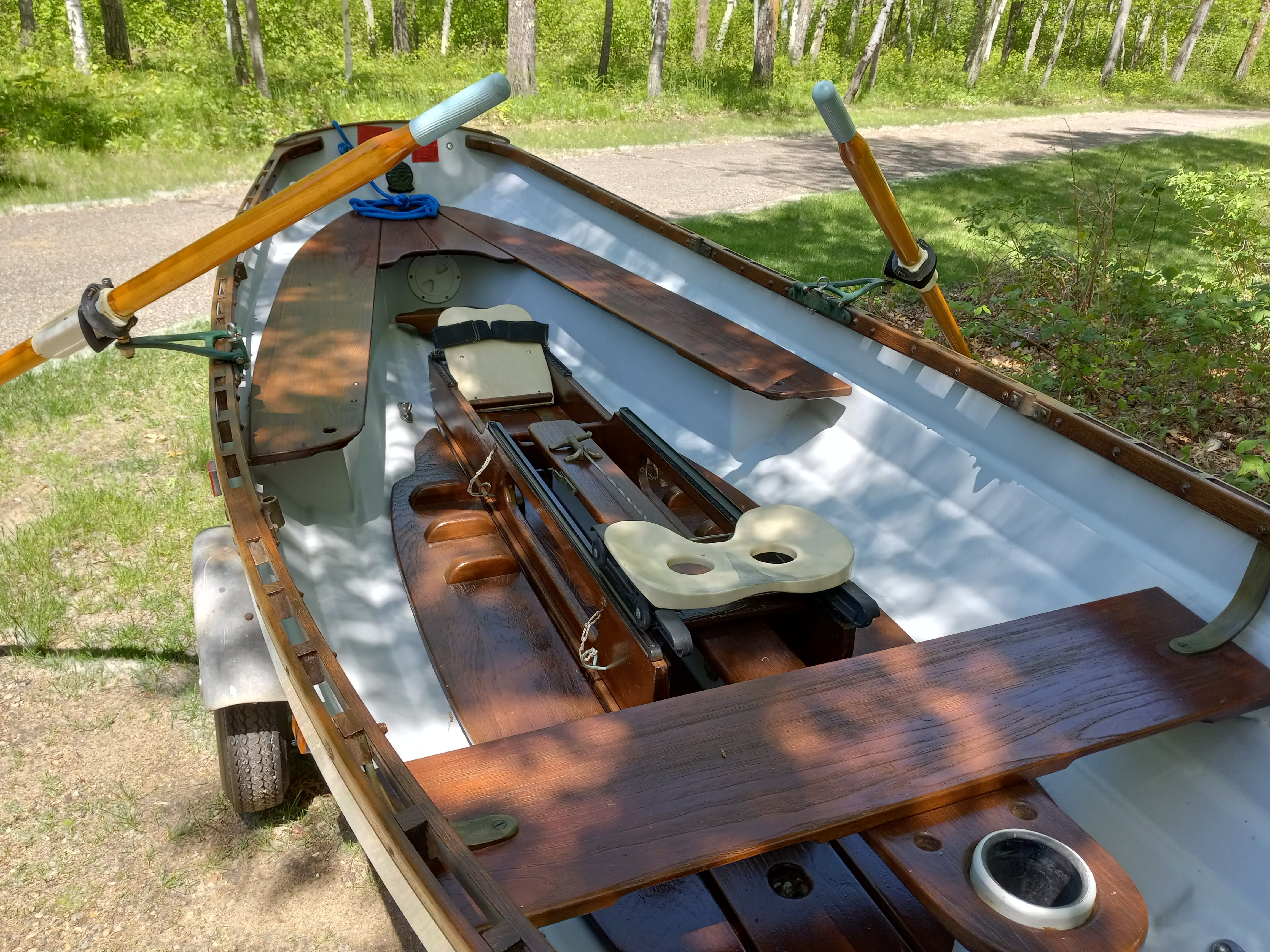 A 2005 Whitehall Spirit 14 rowing boat on a trailer in a wooded area.