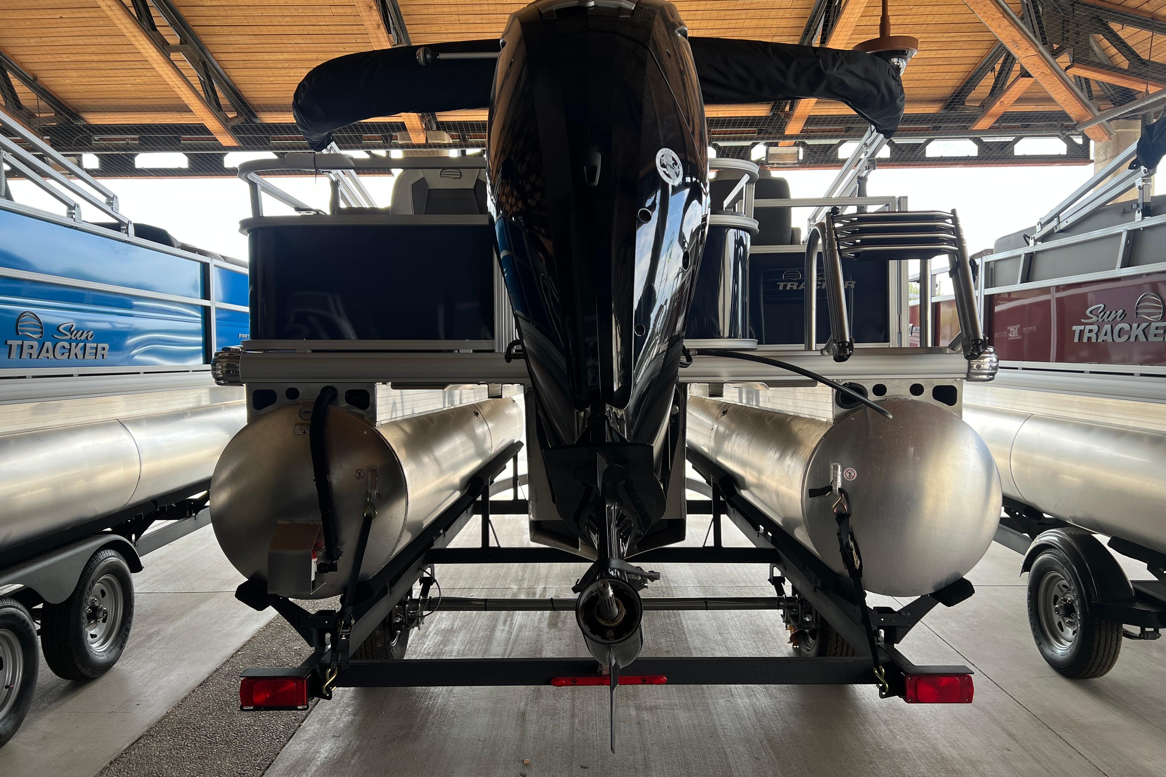 2026 Sun Tracker Bass Buggy 18 DLX pontoon boat on trailer in storage facility.