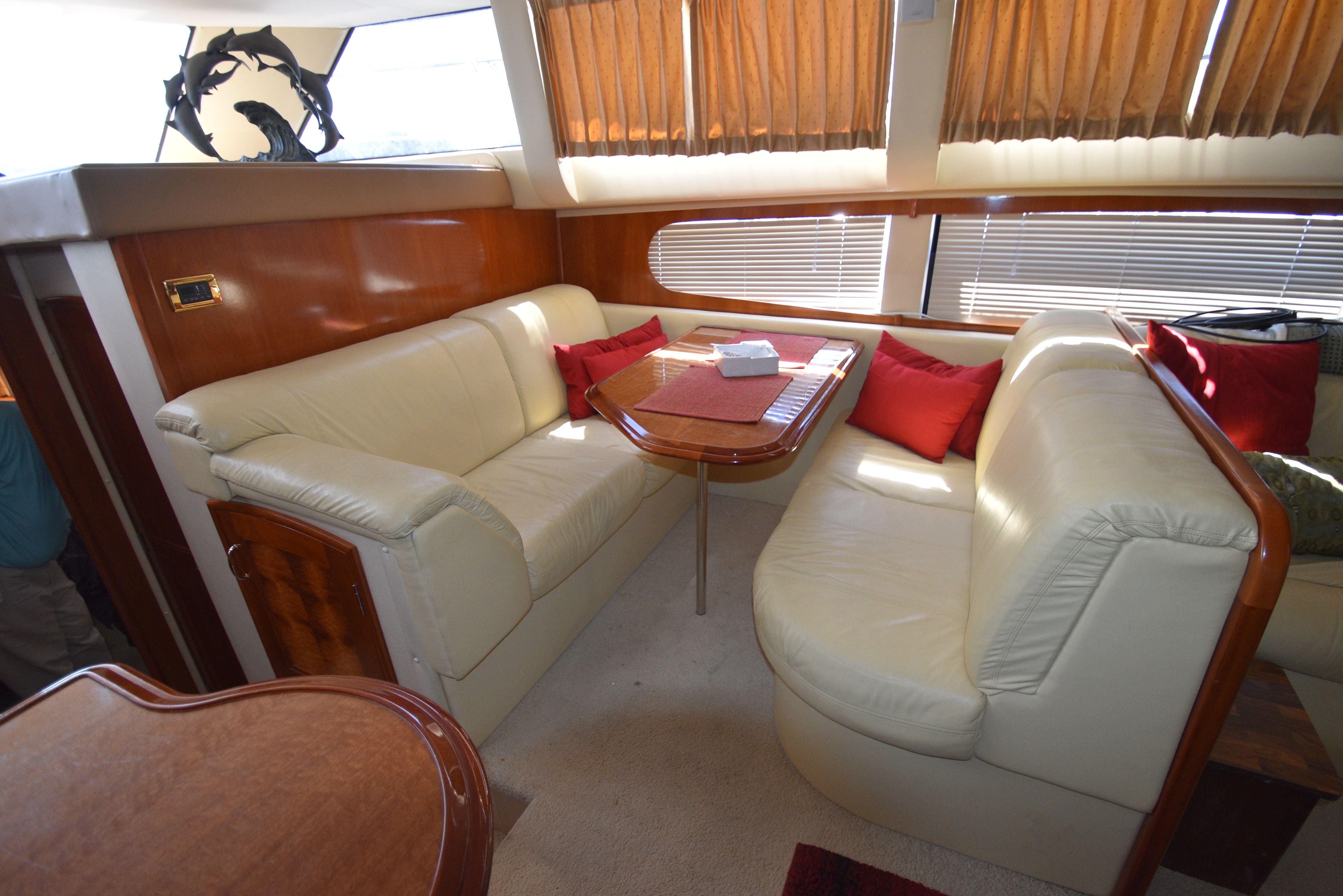 Interior of a 2004 Carver 466 Motor Yacht with beige leather sofas and a wooden table.