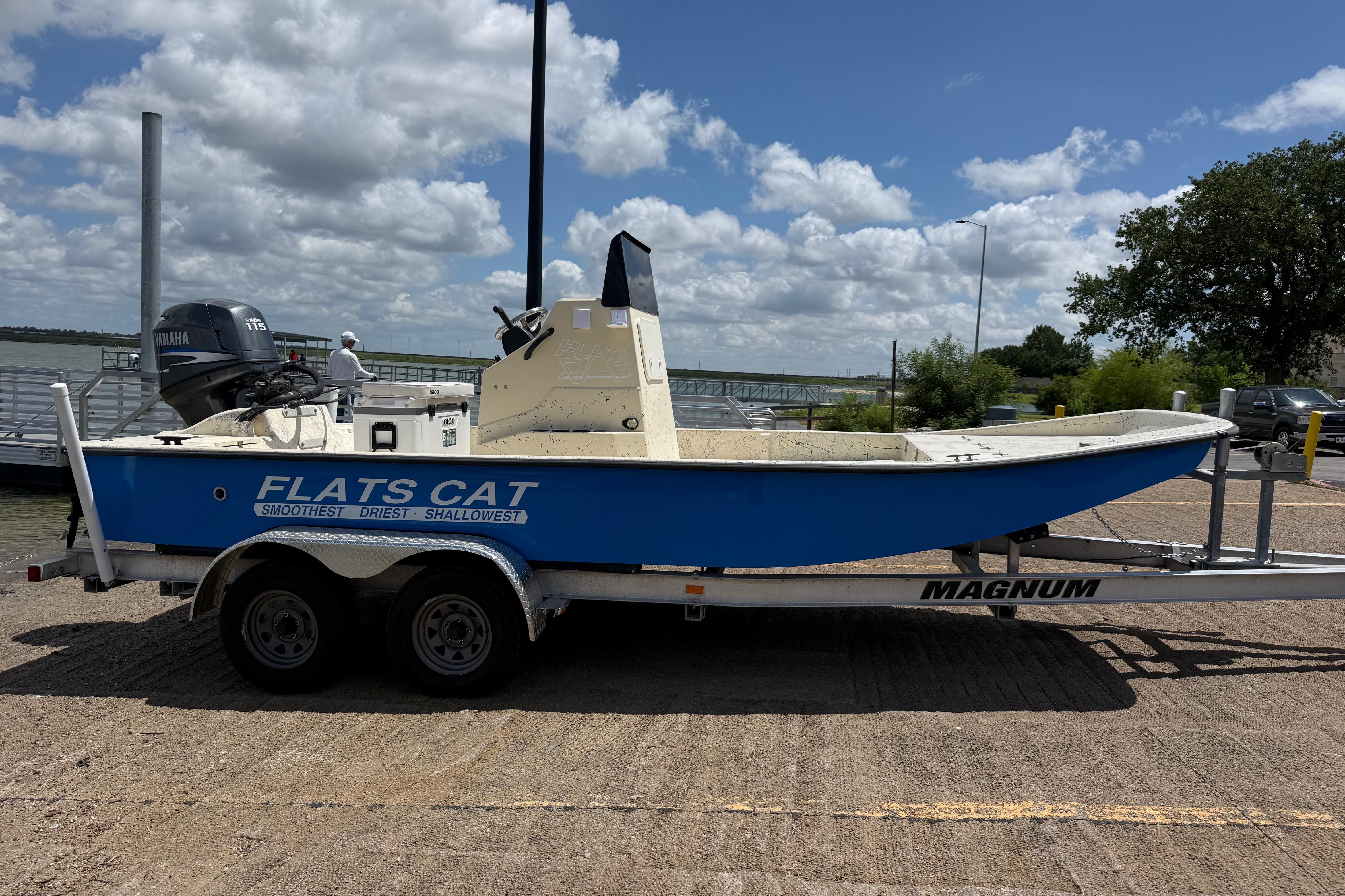 2007 Flats Cat 19 boat on trailer, blue hull, Yamaha motor, dockside under cloudy sky.