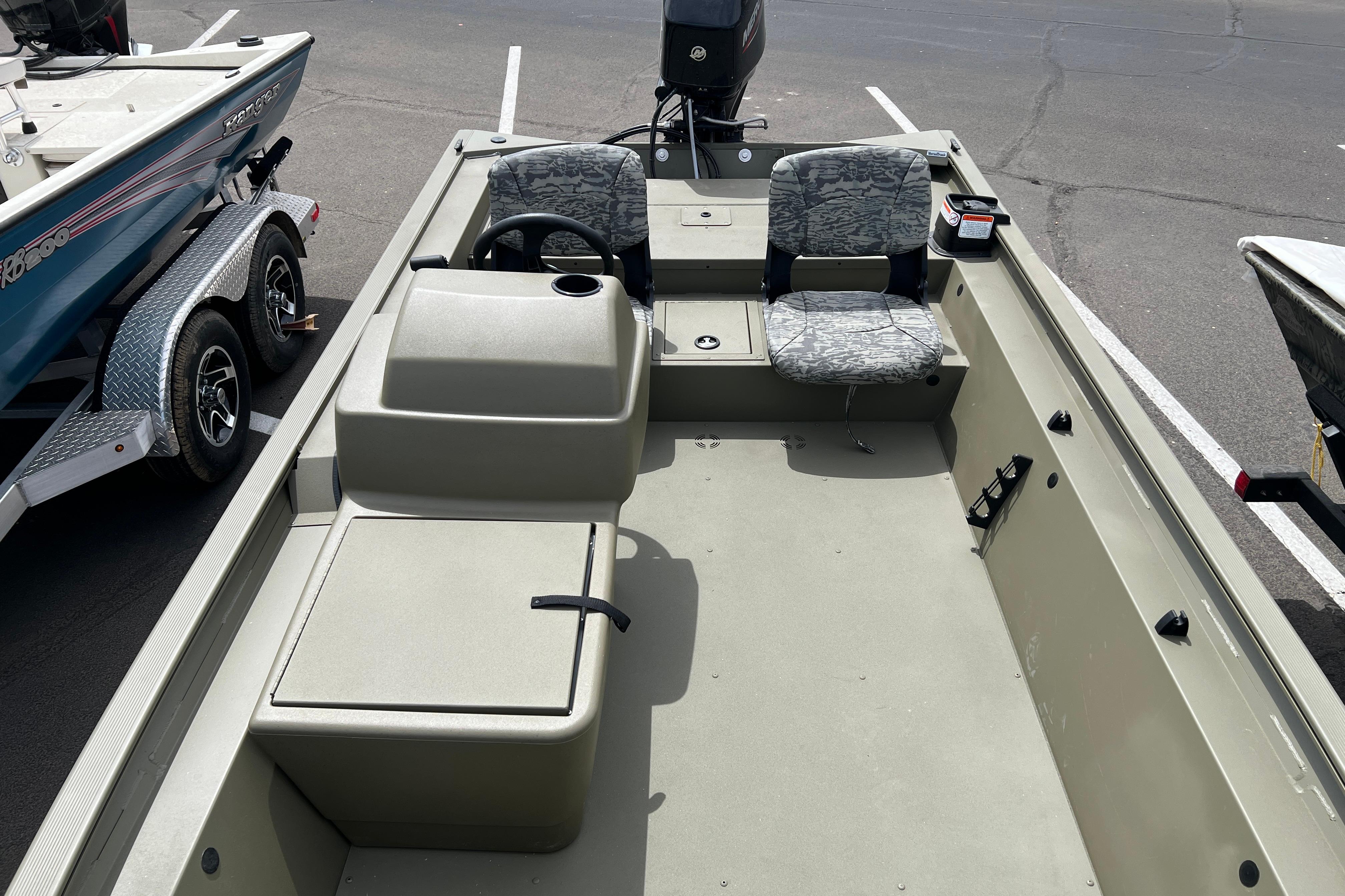 2026 Tracker Grizzly 1754 SC boat interior with seating and steering console in a parking lot.