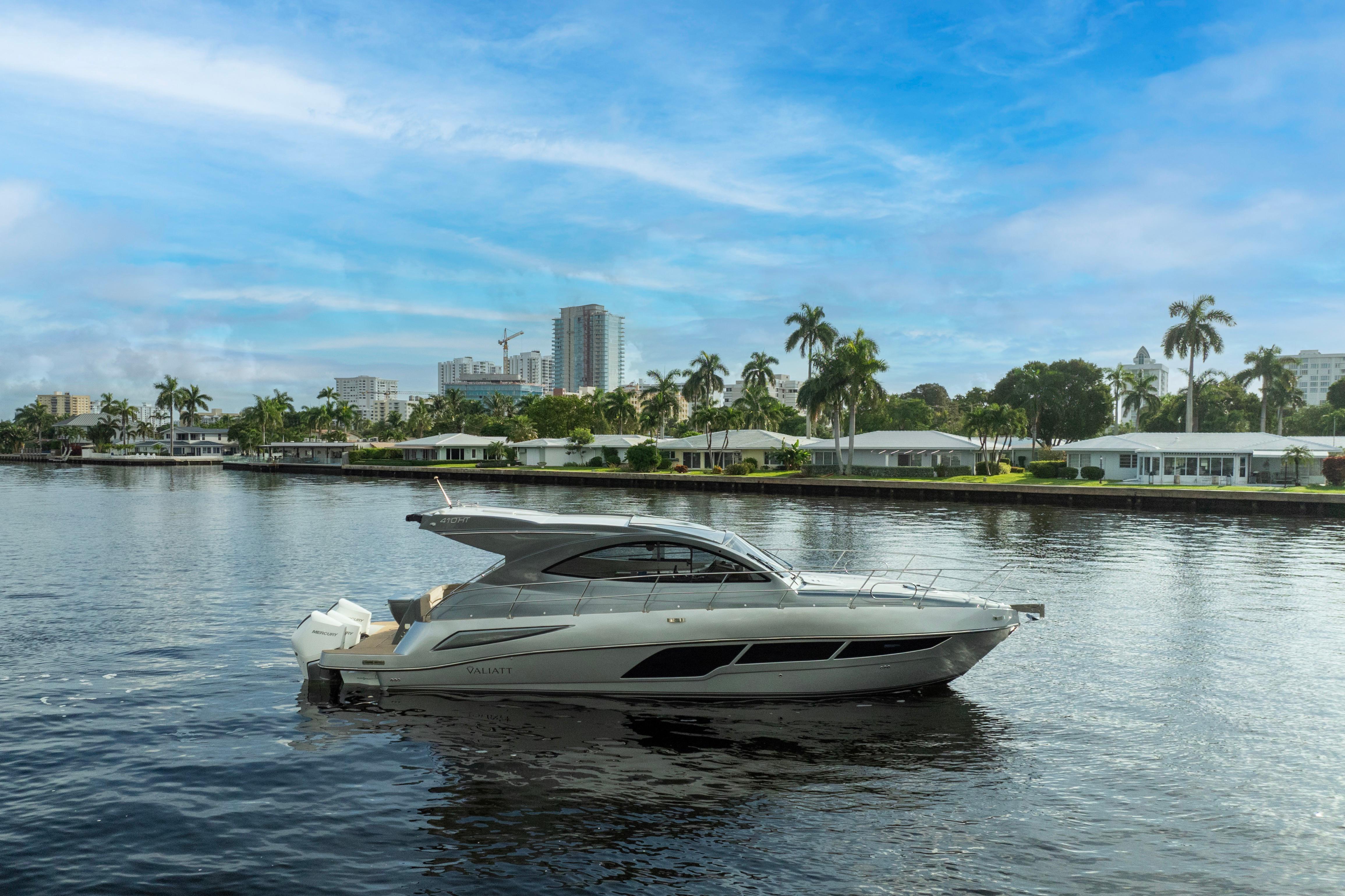 2025 Valiatt 410HT yacht cruising on a serene waterway with cityscape backdrop.