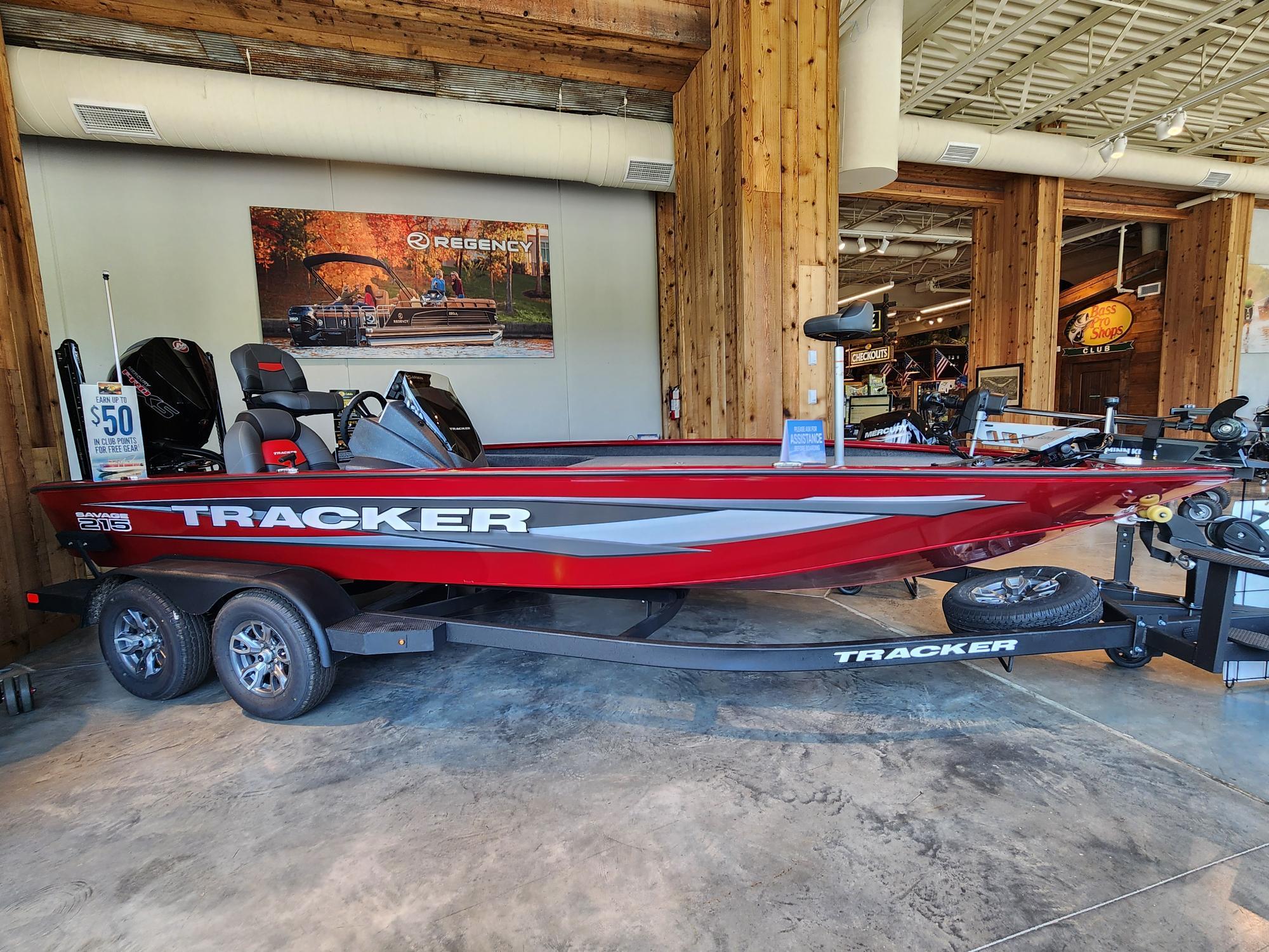 A red Tracker Savage 215 boat is displayed in a showroom.