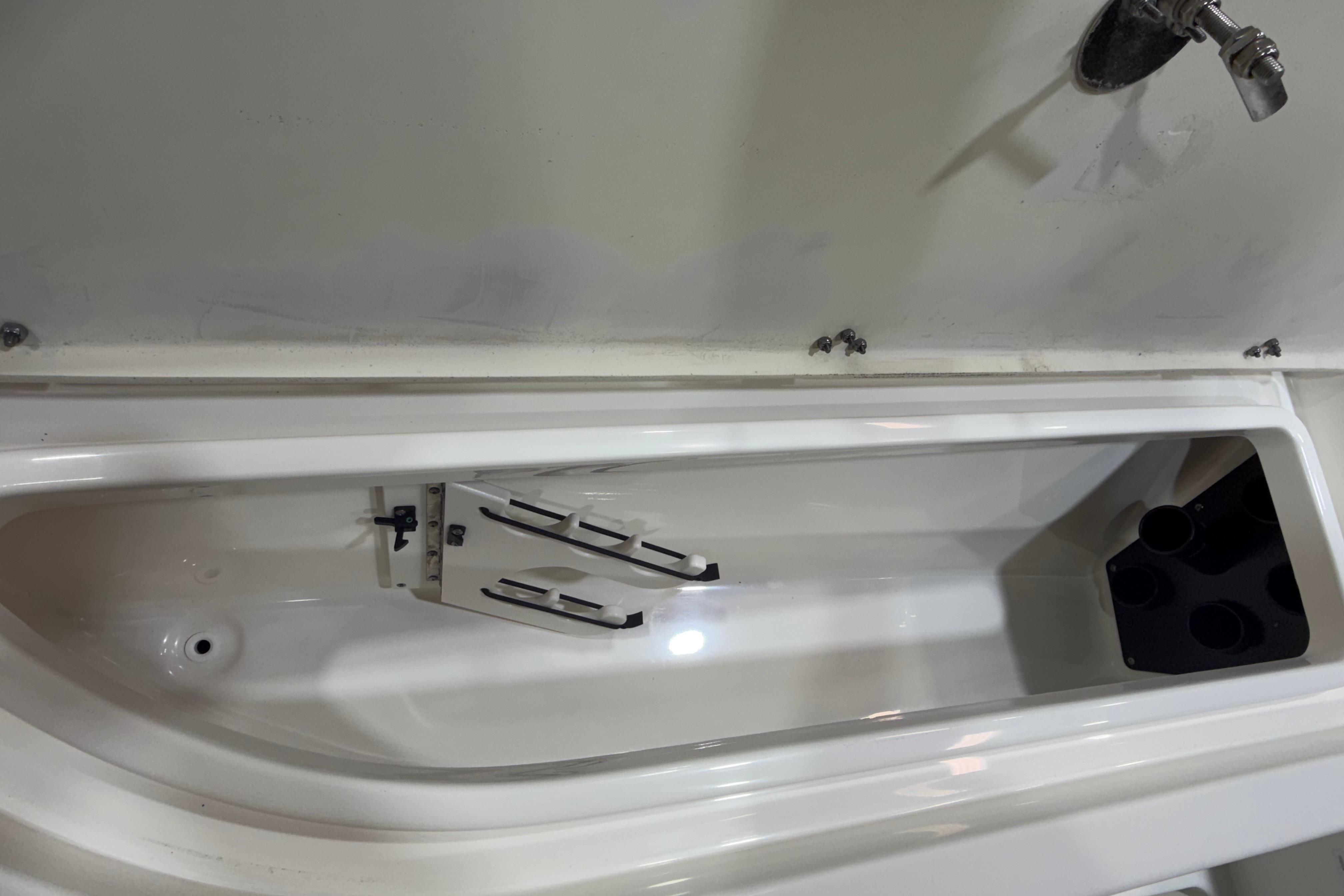 2023 NauticStar 215 XTS boat storage compartment with rod holders and drainage system.