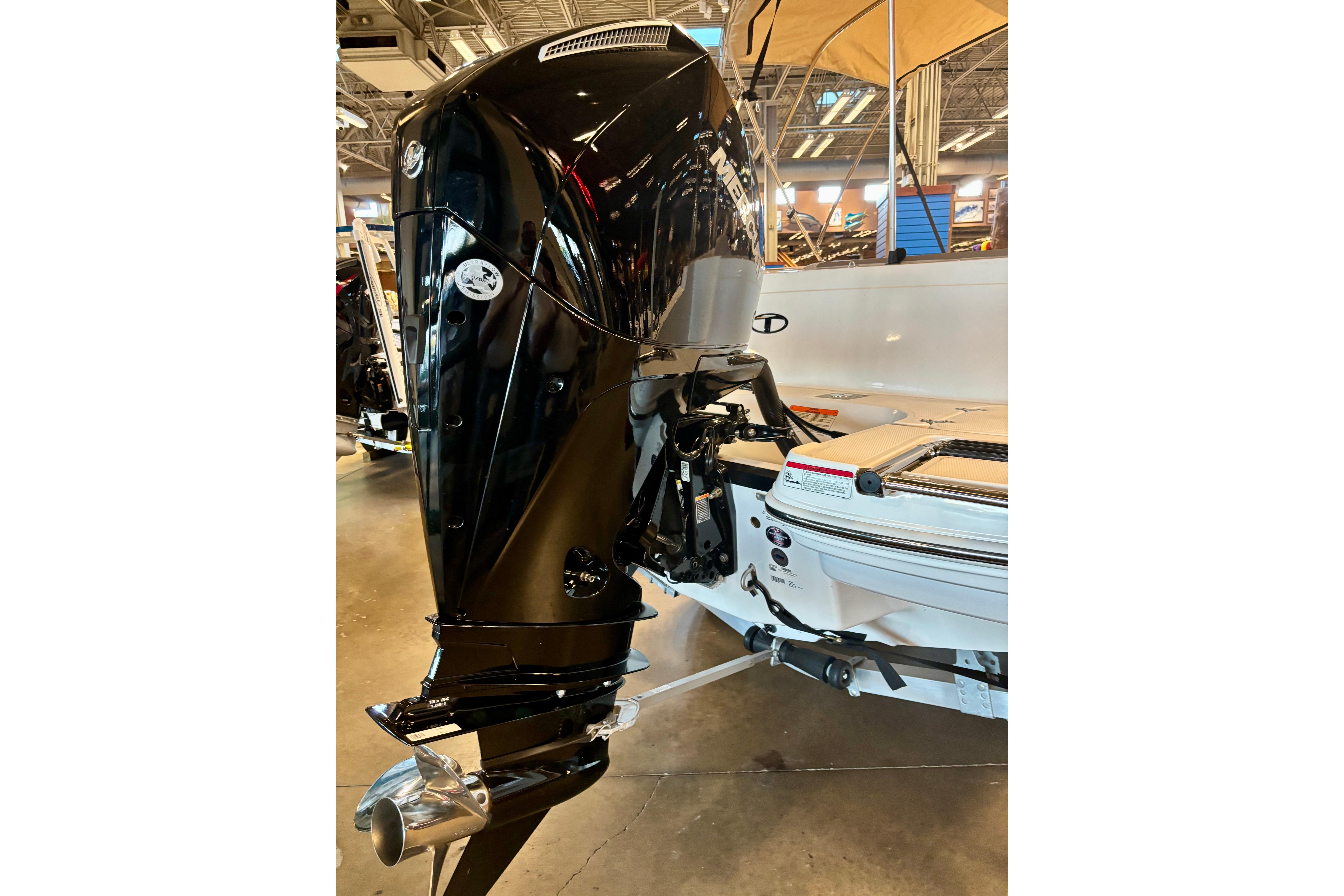 2026 Tahoe 2150 boat with a sleek black outboard motor in showroom.