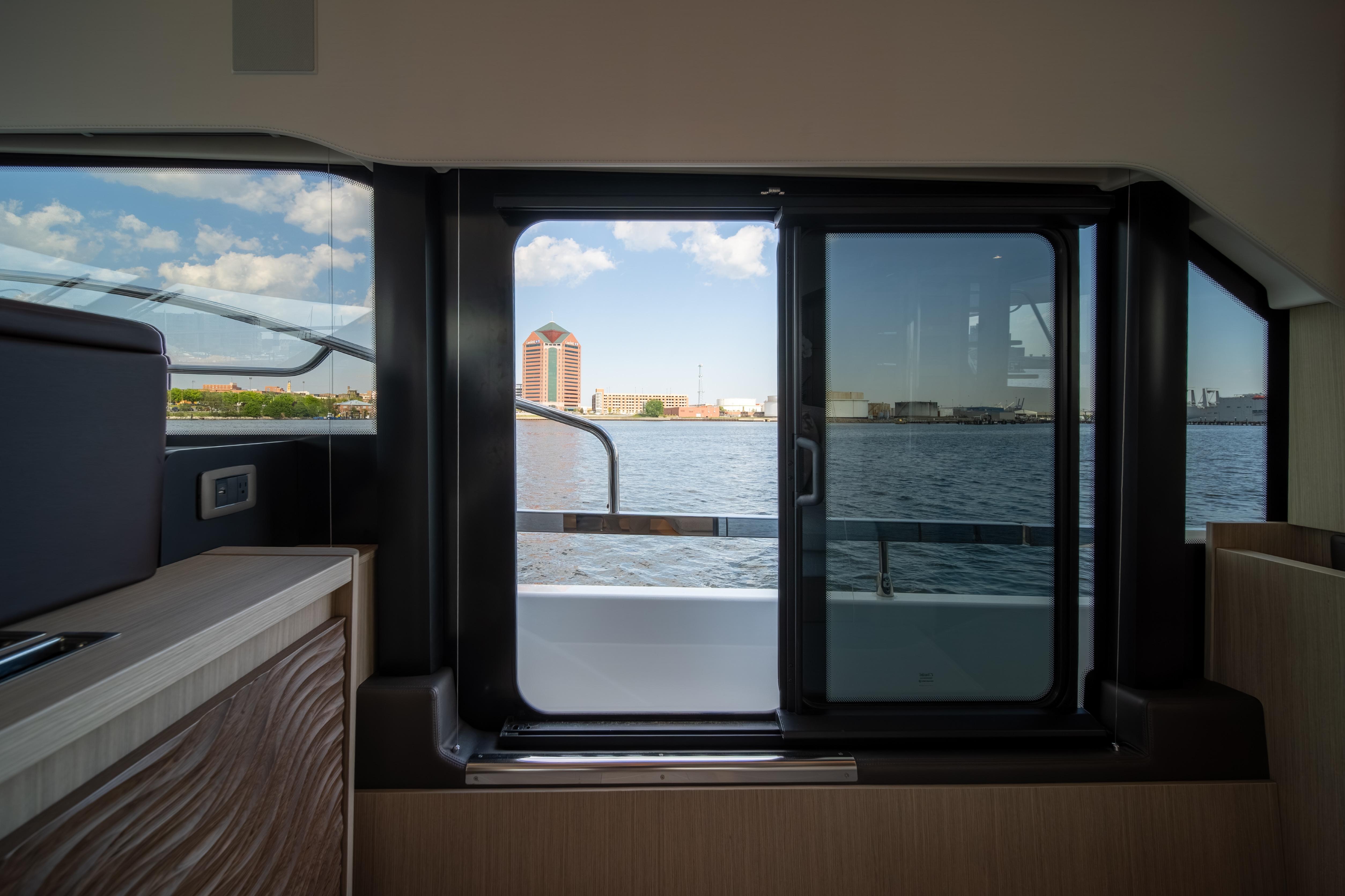 Interior view from Prestige F4.9 yacht, showcasing waterfront cityscape through large windows.