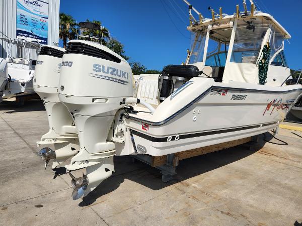 2005 Pursuit 3070 Offshore Center Console boat with twin Suzuki engines, docked outdoors.