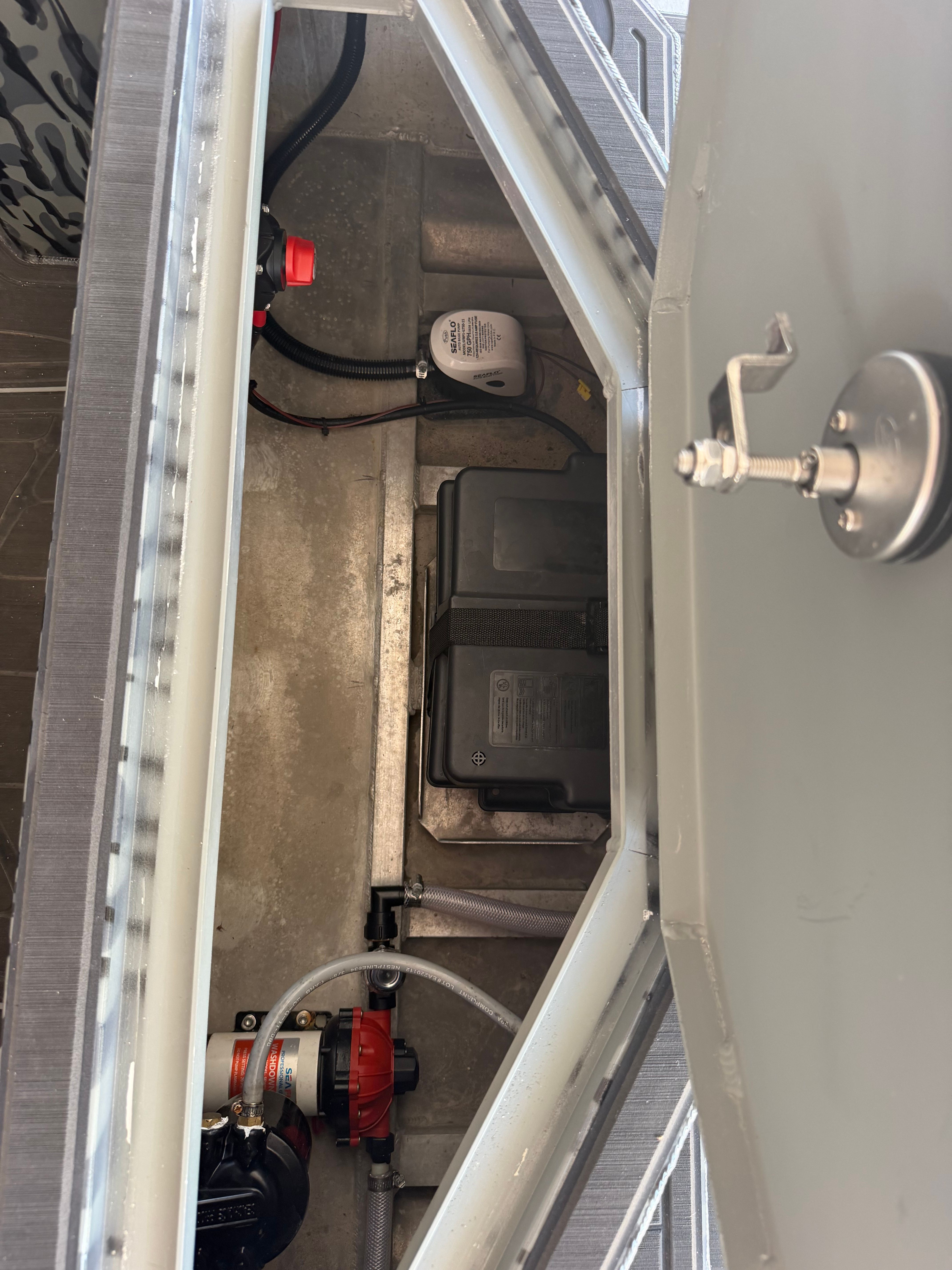 An open compartment with batteries and cables on a boat.