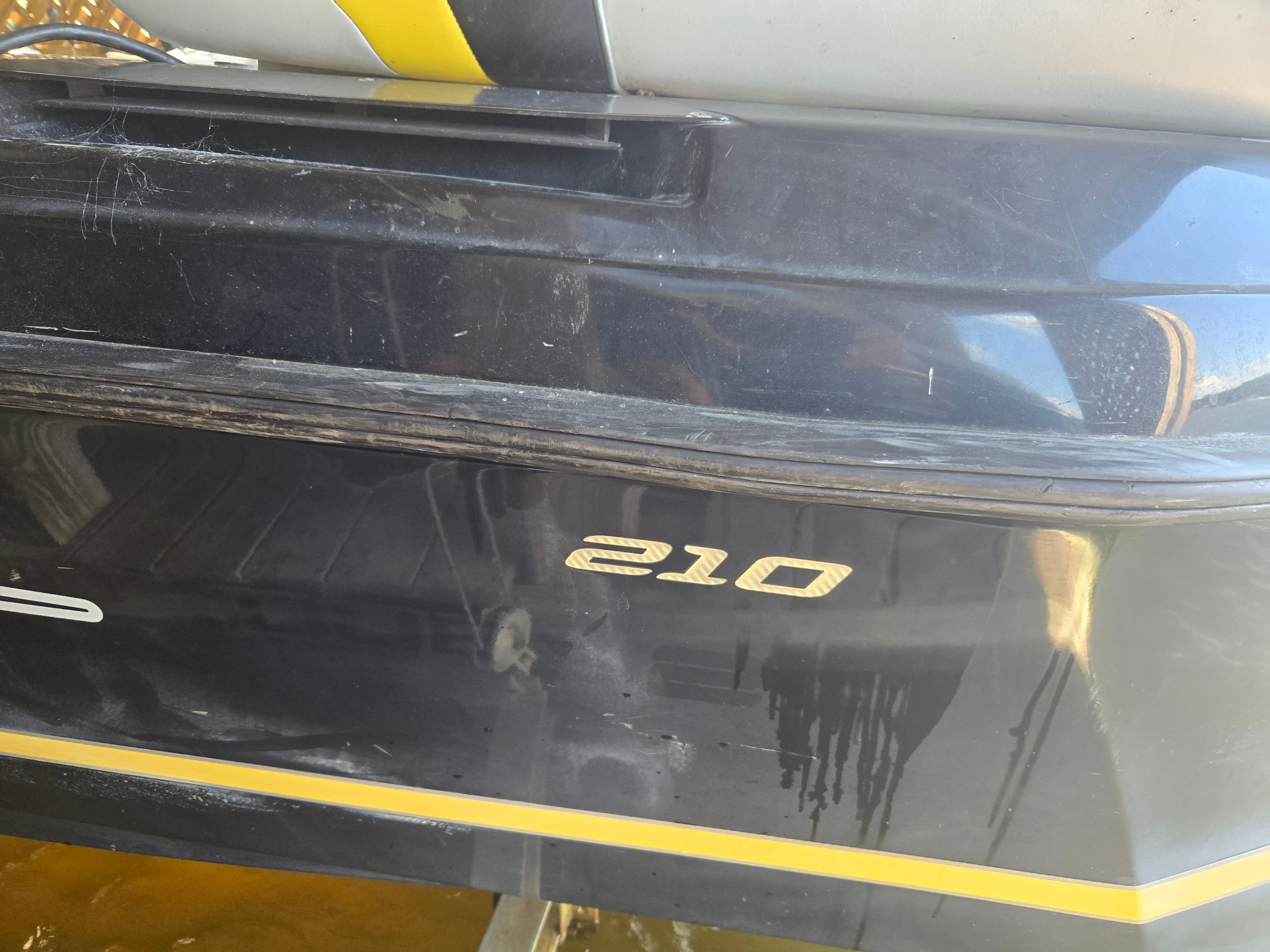 Close-up of a black boat hull with yellow stripes and the number "210."