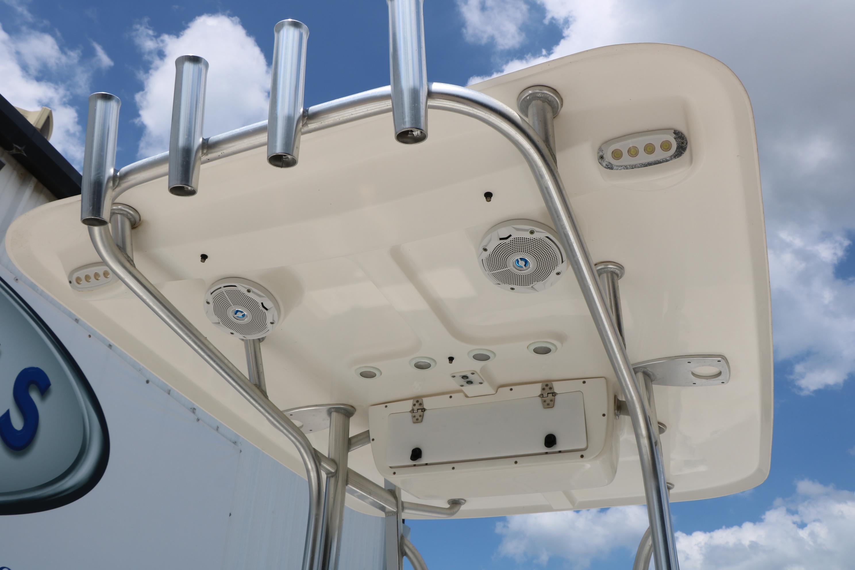 2015 Sea Hunt BX 22 BR boat T-top with rod holders and speakers against blue sky.