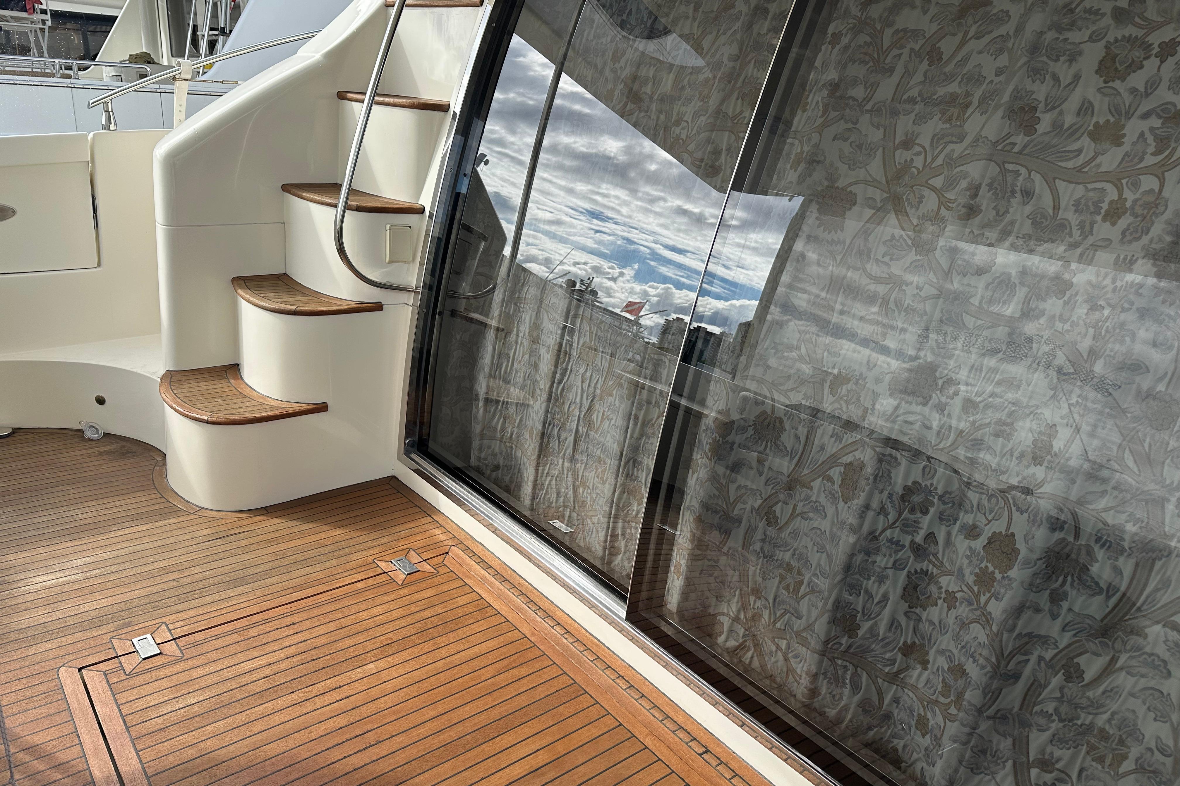 2004 Azimut 55E yacht deck with wooden flooring and elegant staircase.