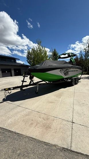 A 2018 Nautique Super Air Nautique G23 on a trailer, covered, on a concrete lot.