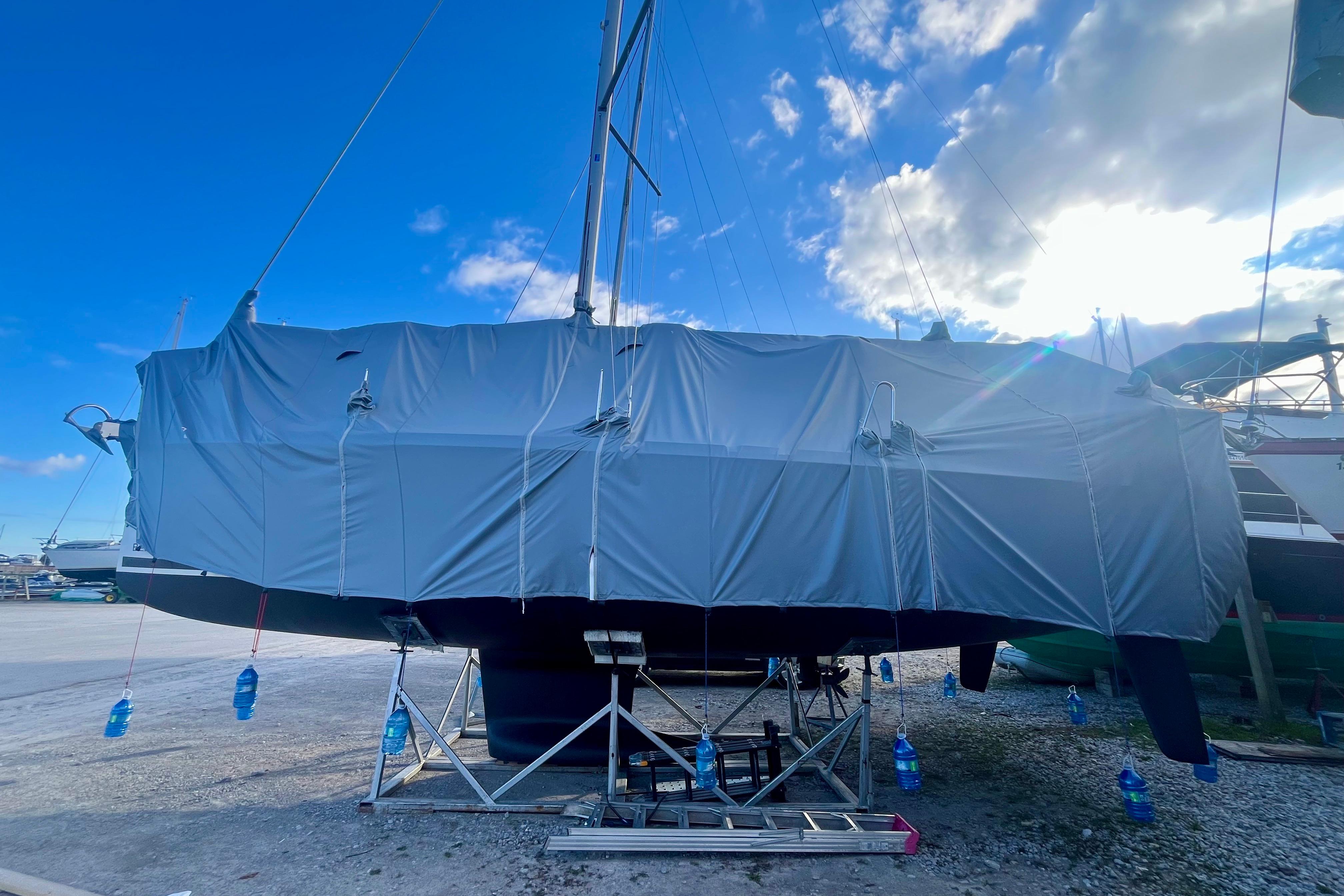 Covered 2019 Beneteau Oceanis 35.1 sailboat on a stand under a blue sky.