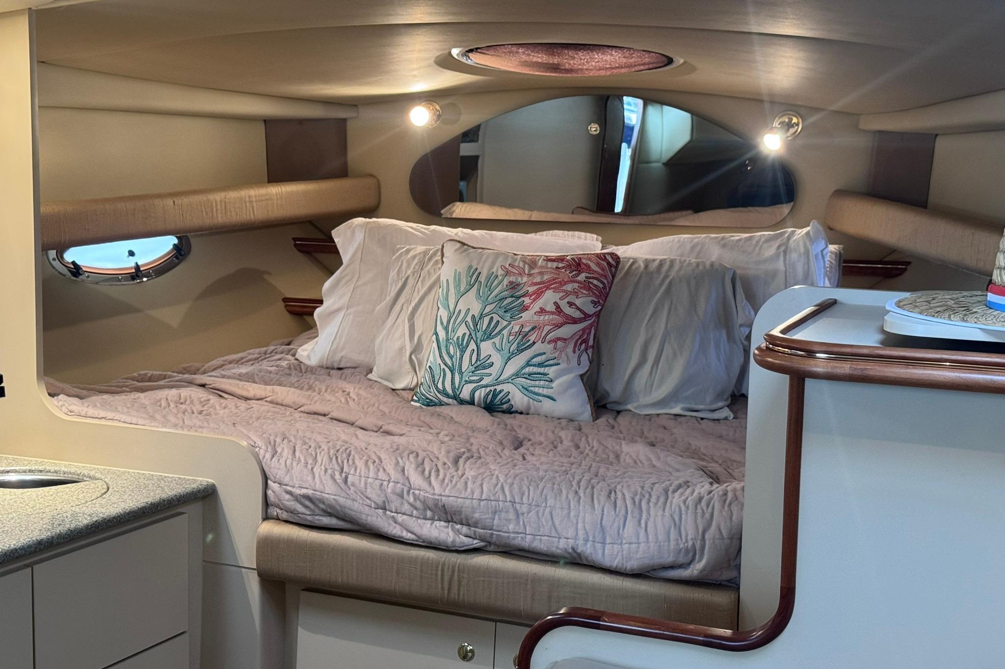 Cozy cabin interior of 2002 Cruisers Yachts 3275 Express with plush bedding and decorative pillows.