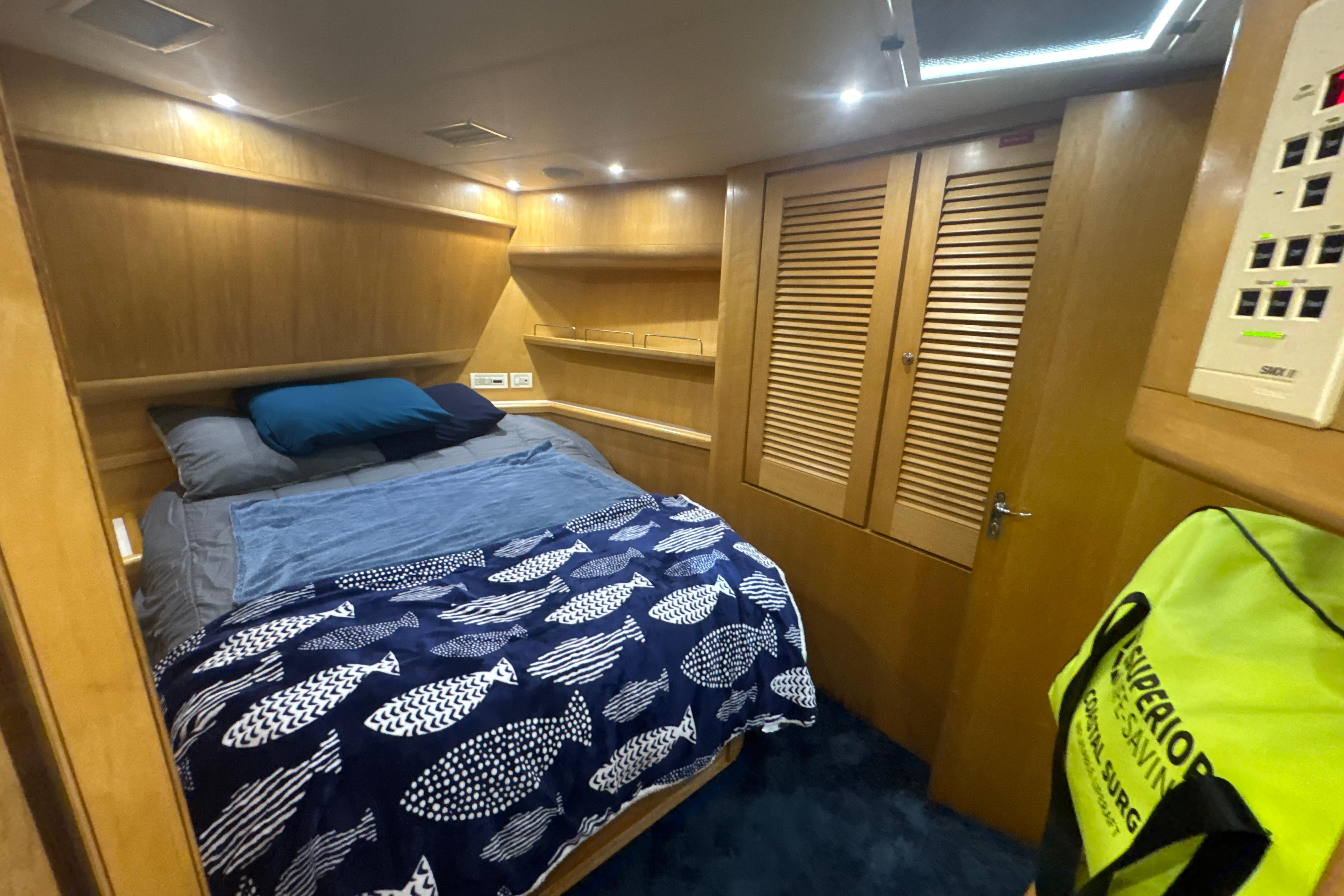 Cozy cabin interior of a 1997 Bertram 54 Convertible yacht with wooden accents and nautical bedding.