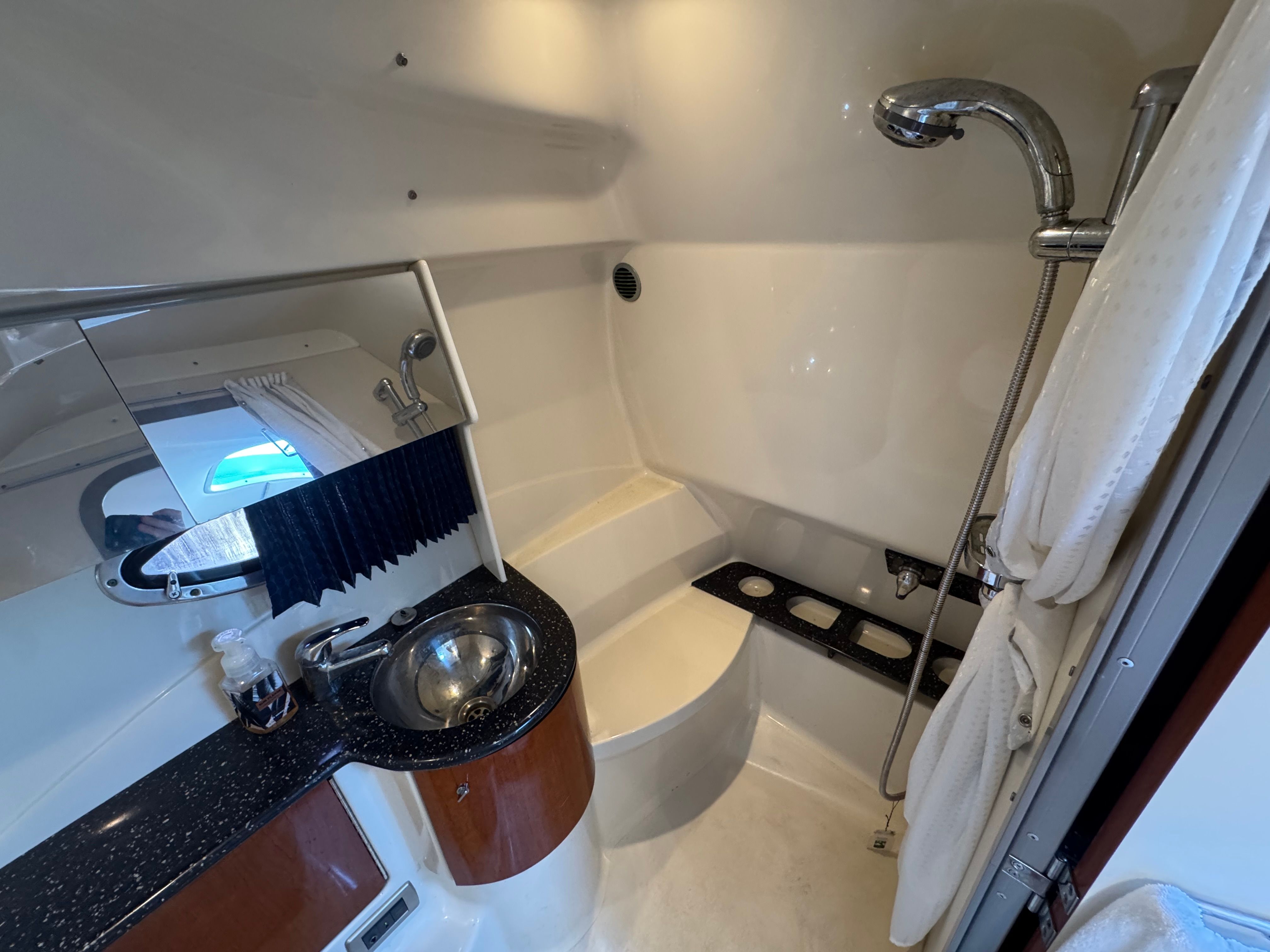 A sleek bathroom with a sink, mirror, and shower inside a boat.