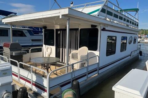 1995 Myacht 40X13 houseboat docked, featuring outdoor seating and grill on the deck.