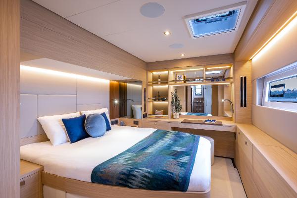 Luxurious 2025 Lagoon 60 yacht bedroom with modern decor and natural lighting.
