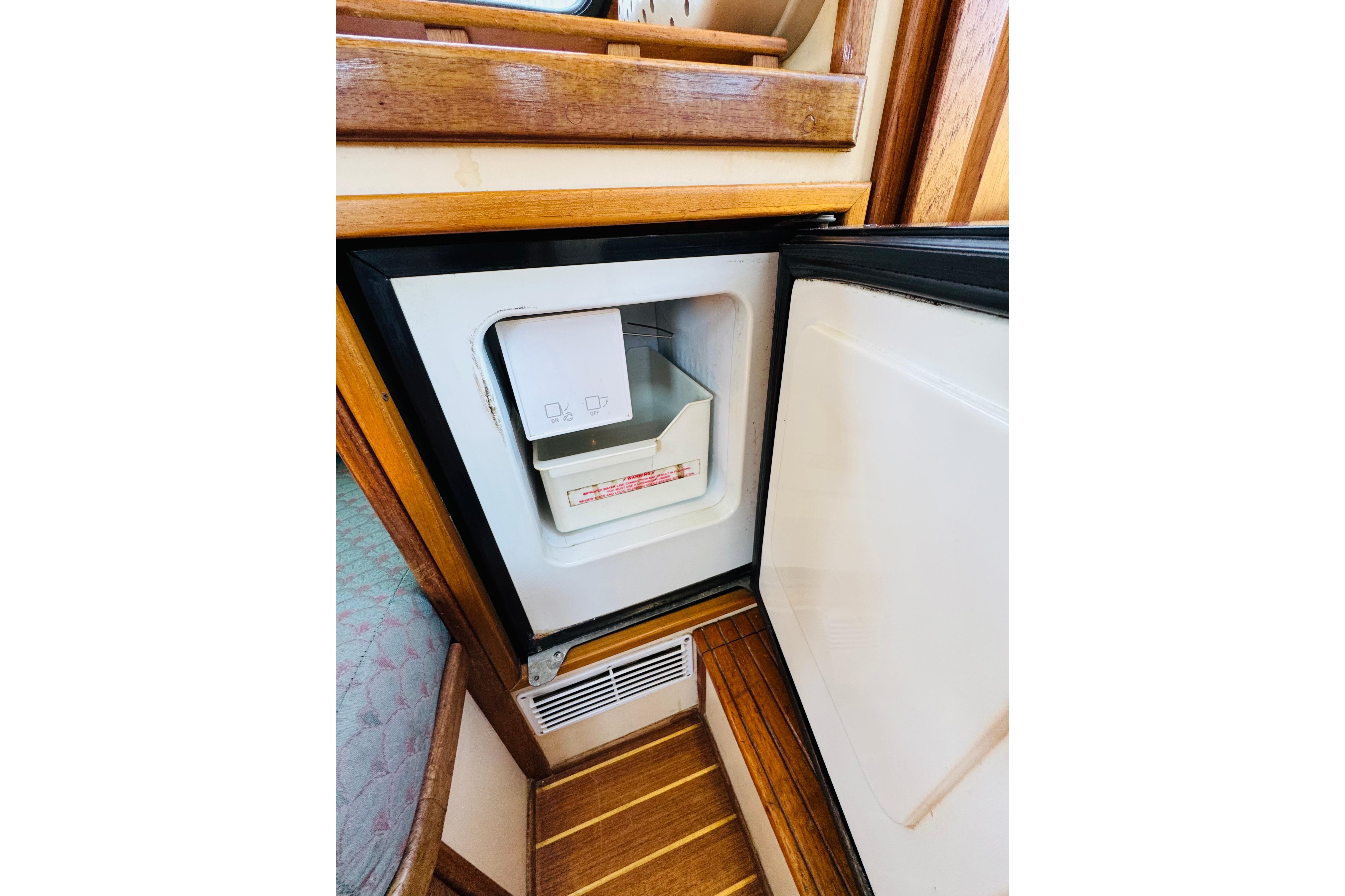Open refrigerator inside 1996 Nordic Tug 32 boat, showcasing wooden interior design.