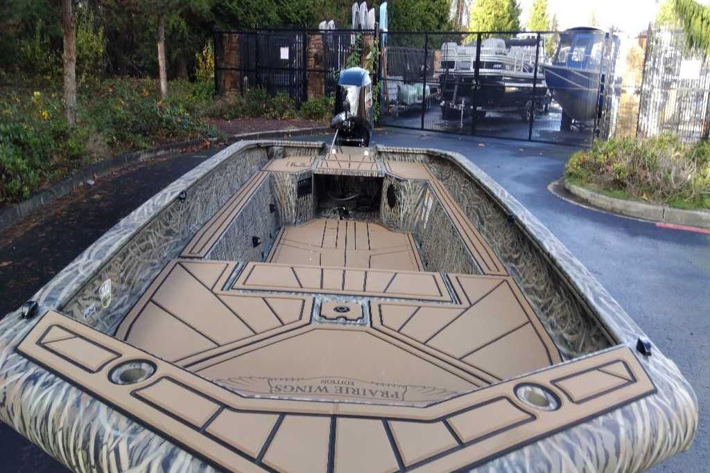 2026 Tracker Grizzly 1650 T Prairie Wings Edition boat with camouflage design in a parking area.