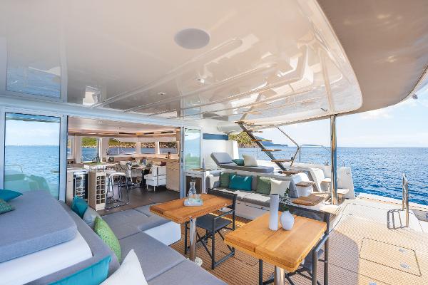 Luxurious 2025 Lagoon 60 yacht interior with ocean view, featuring modern seating and dining area.