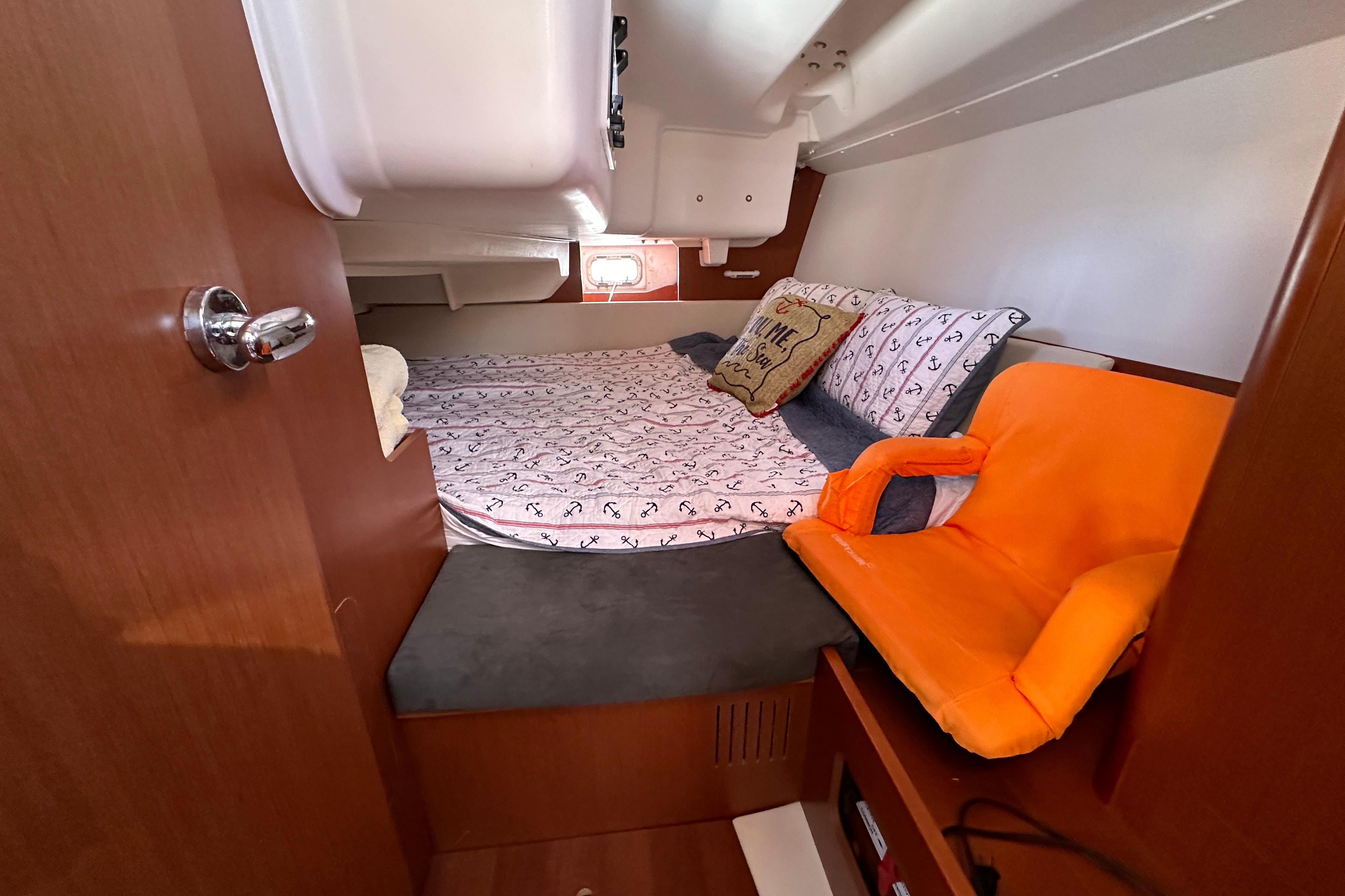 Cozy cabin interior of 2015 Beneteau Oceanis 37 with bed and orange seat.