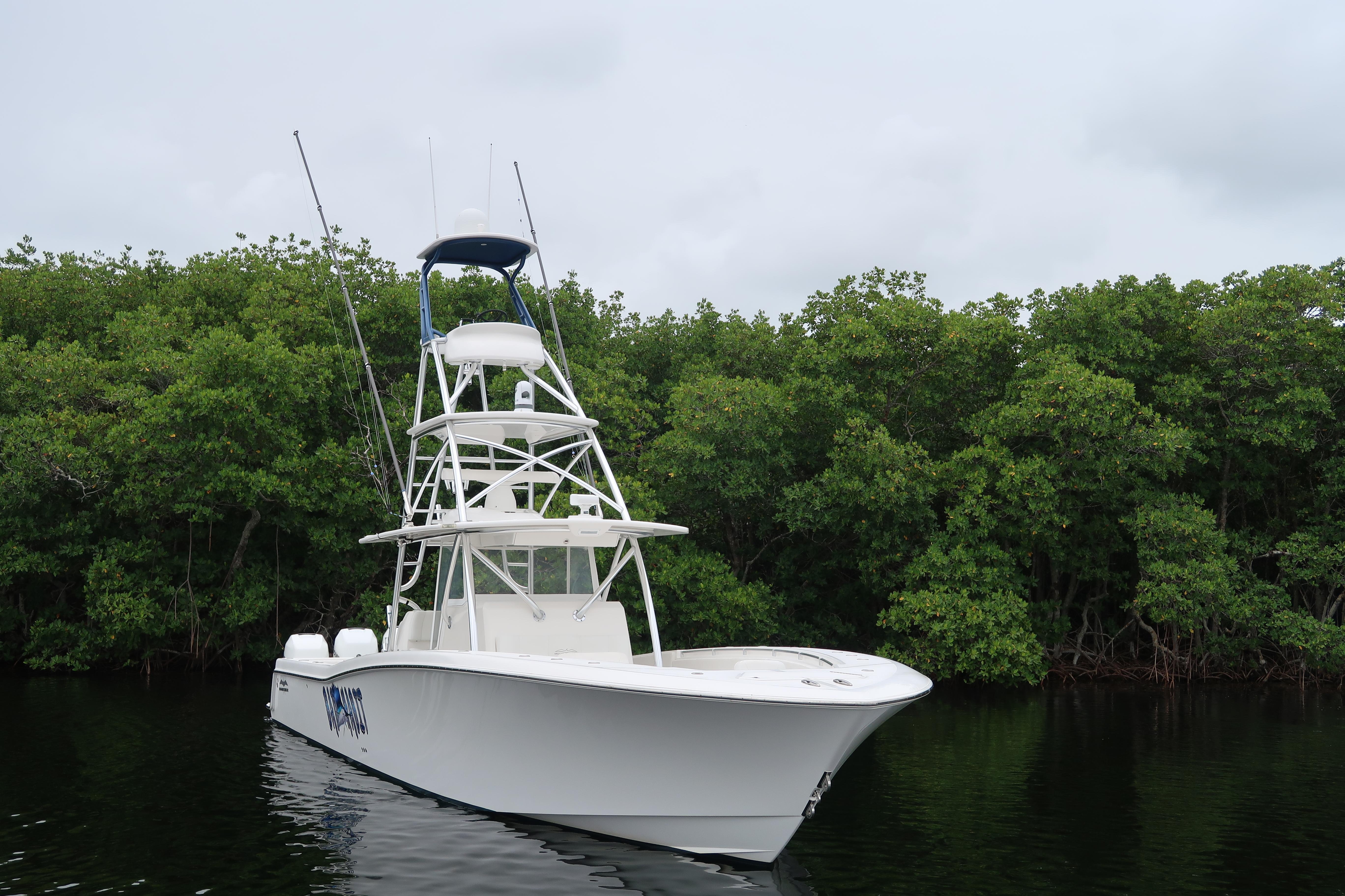 2016 Invincible 42 Open Fisherman boat on calm water near lush greenery.