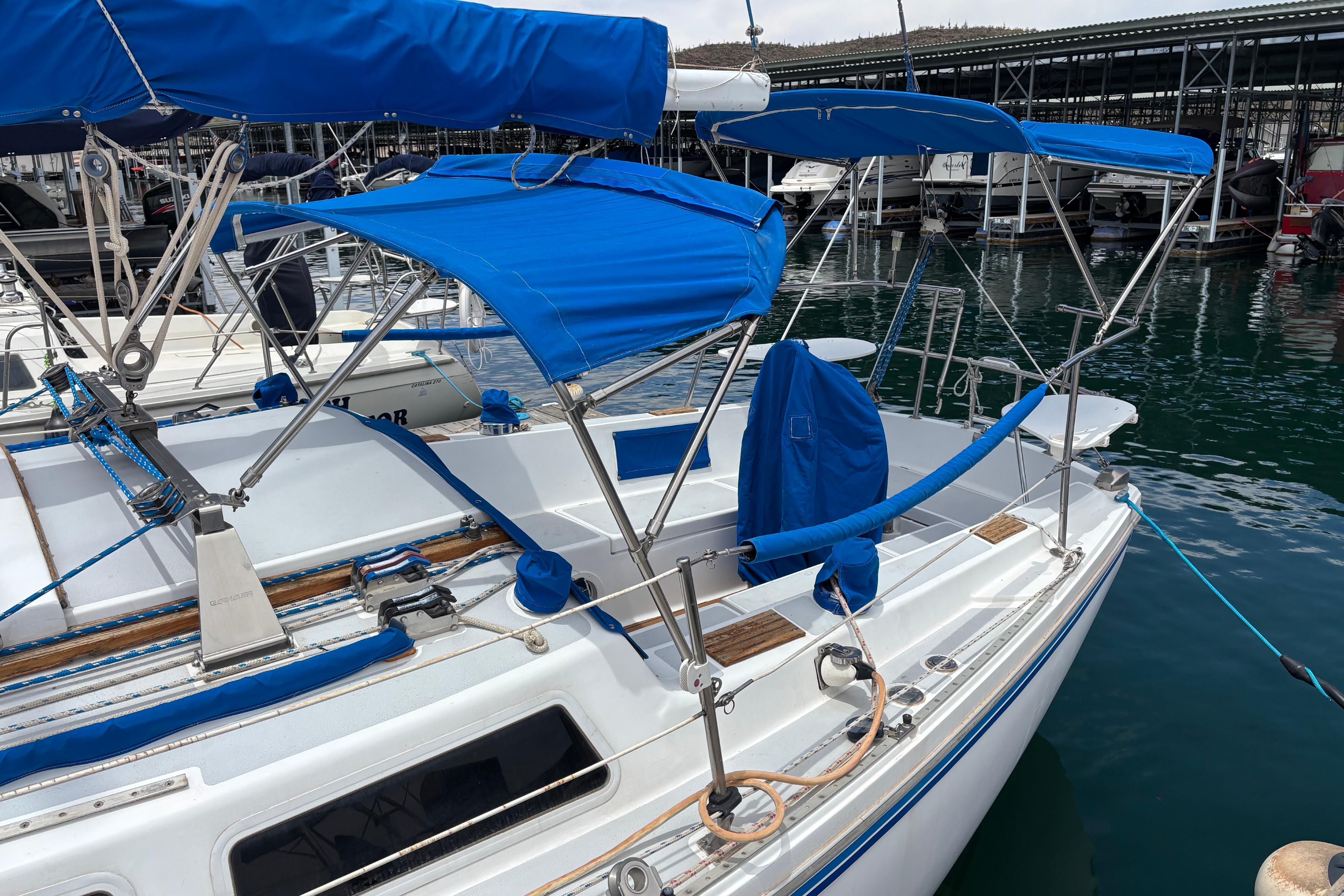 1980 Catalina 30 sailboat with blue canvas covers docked at marina.