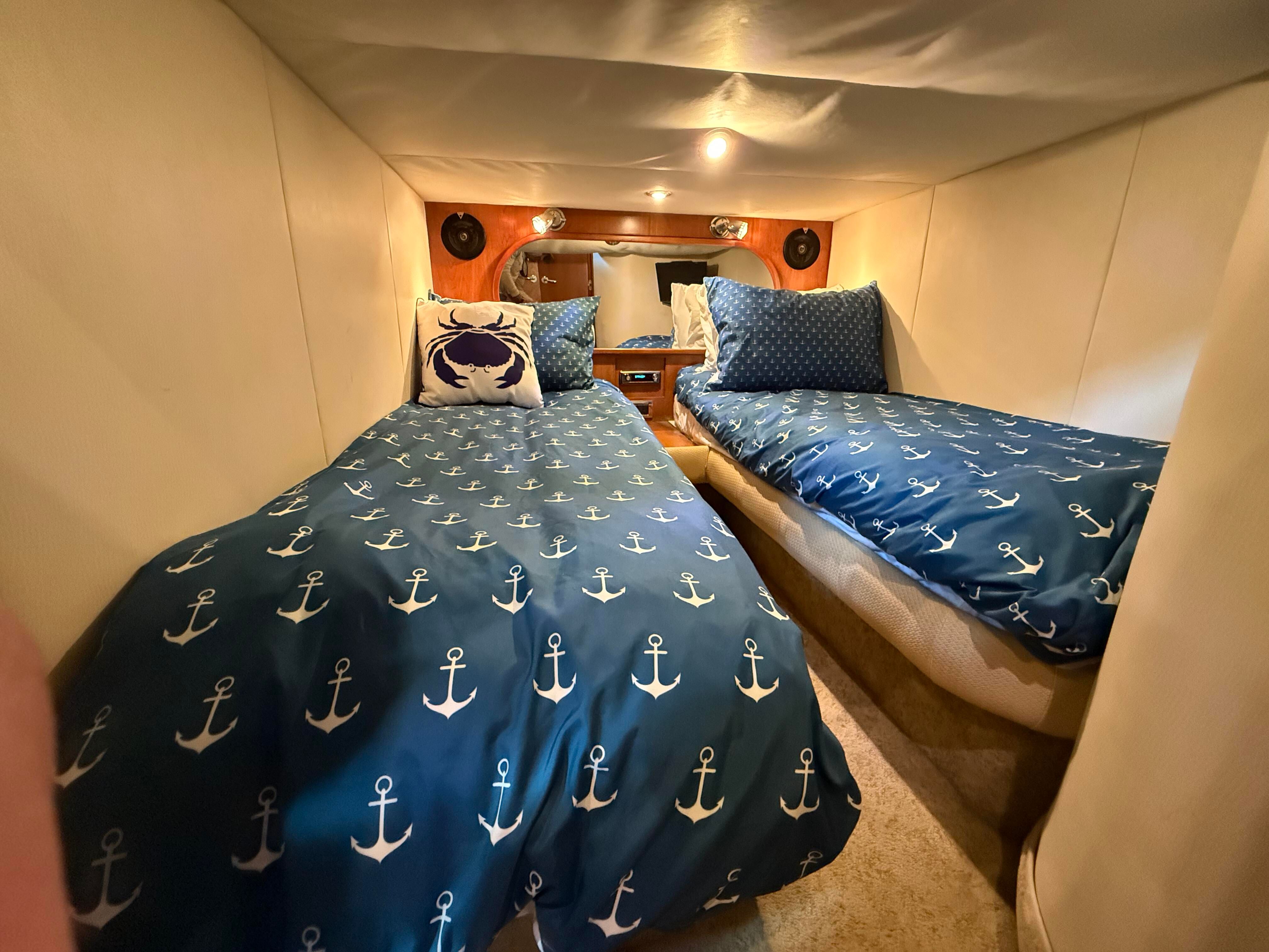 Two single beds with anchor-themed bedding in a cozy cabin.