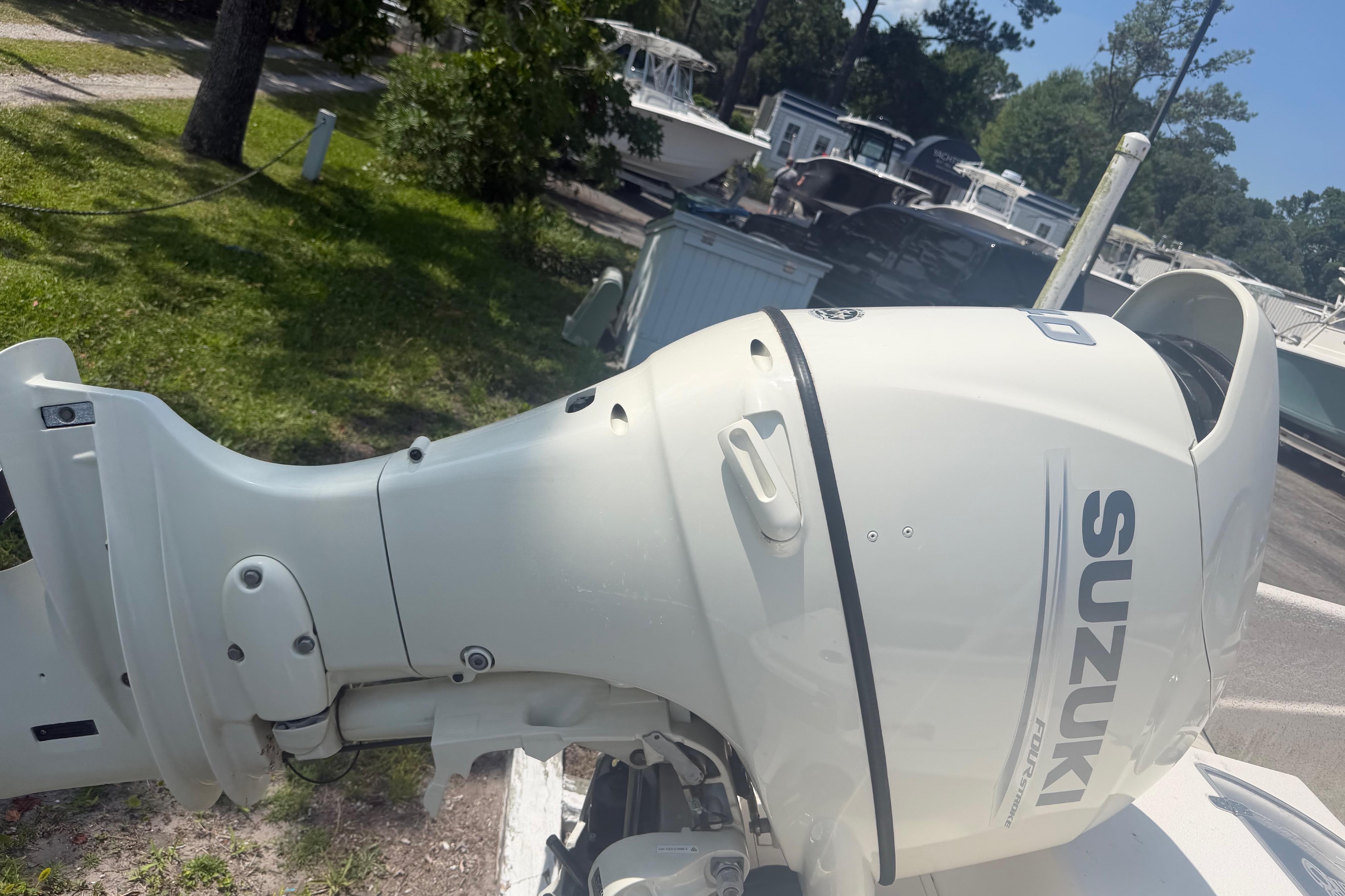 Suzuki outboard motor on a 2019 Carolina Skiff 218 DLV boat, parked outdoors.