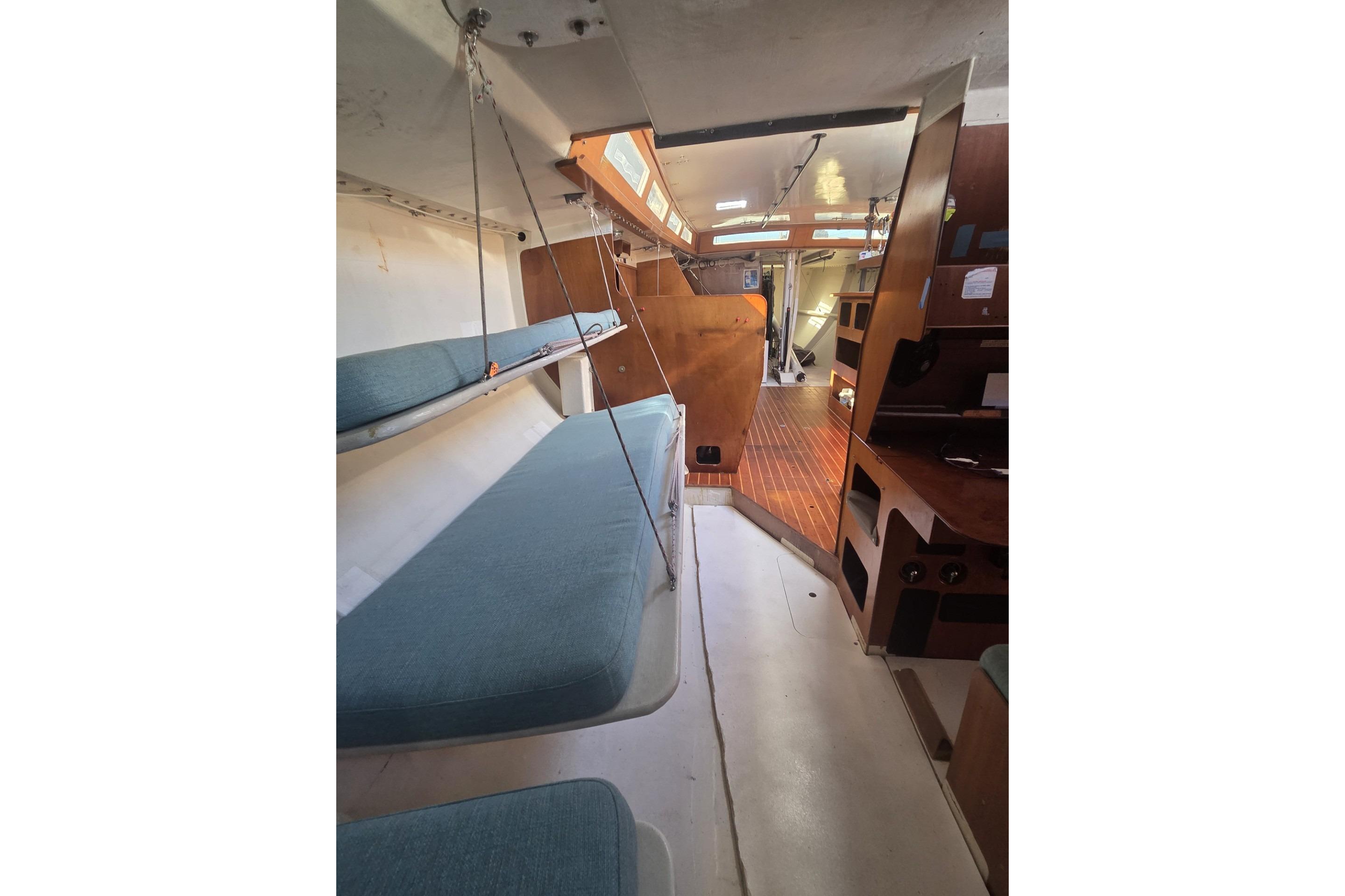 Interior of 1986 Santa Cruz 70 sailboat with blue cushions and wooden accents.